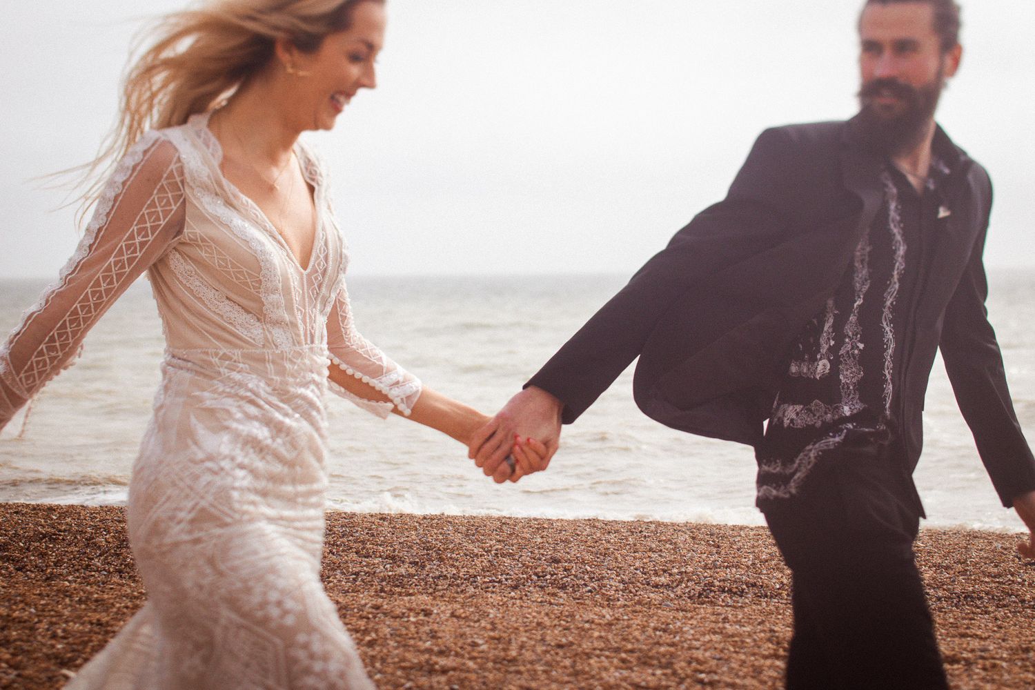 bride and groom running along the beach in soft afternoon light after their ceremony in Brighton