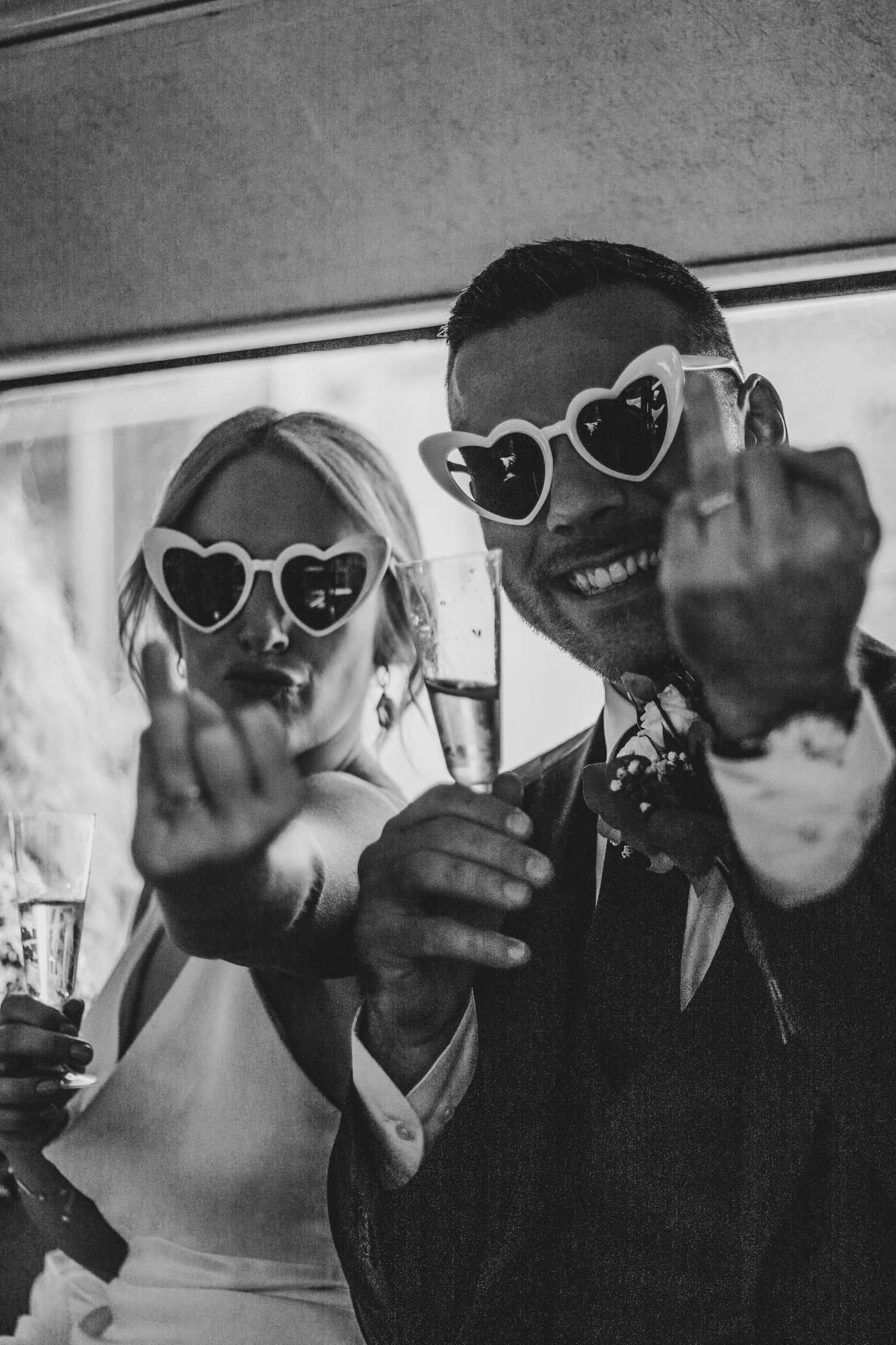 bride and groom holding up their wedding fingers and wearing heart sunglasses after their ceremony at Old Marylebone Town Hall, London