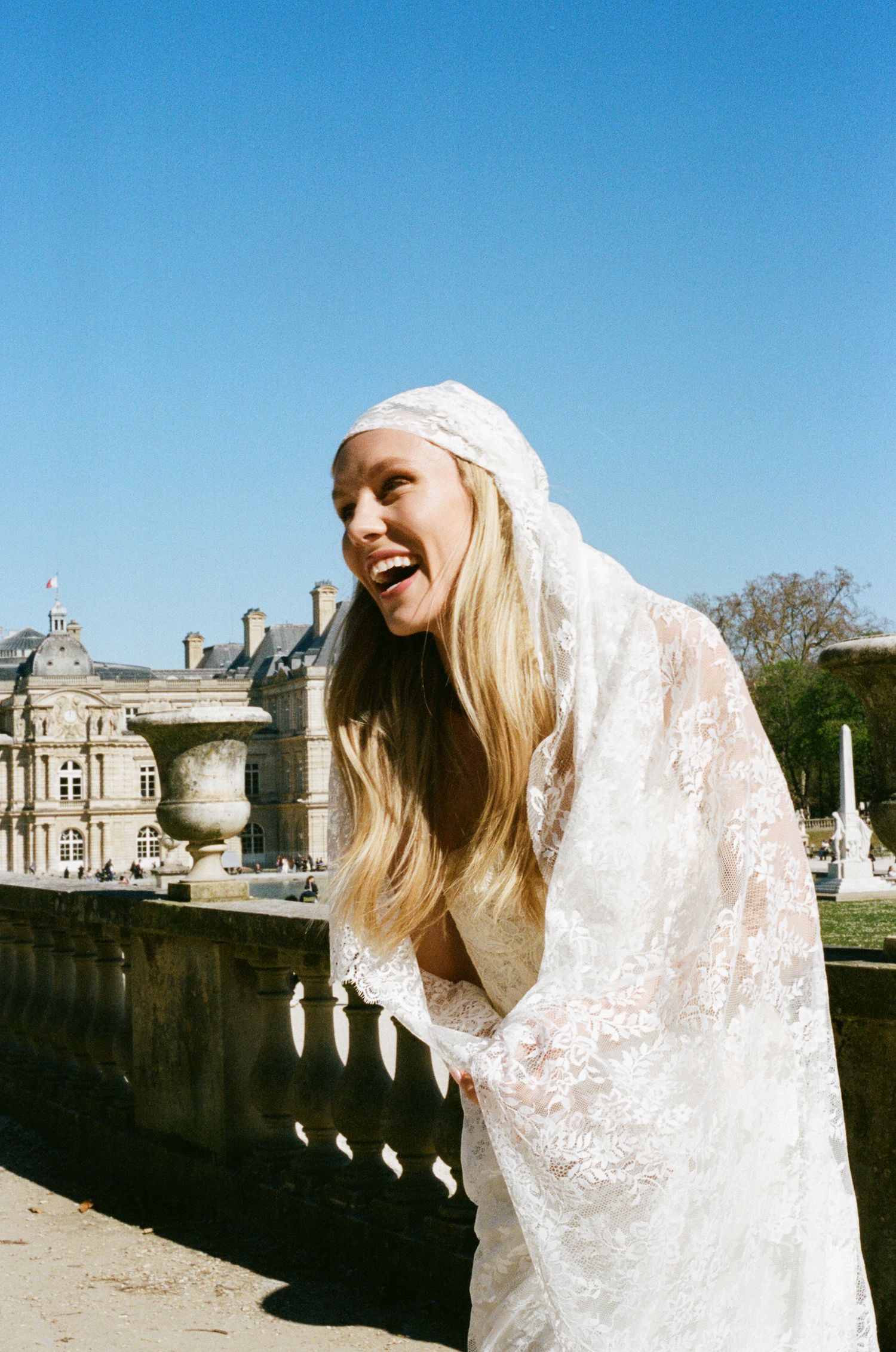 Paris bride white lace veil and gown outdoors at Luxembourg Gardens, Paris, on a sunny day. Stylish paris bride outfit, editorial wedding