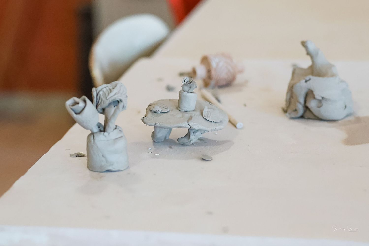 Small handmade clay animal figurines in light gray color displayed on a white surface.