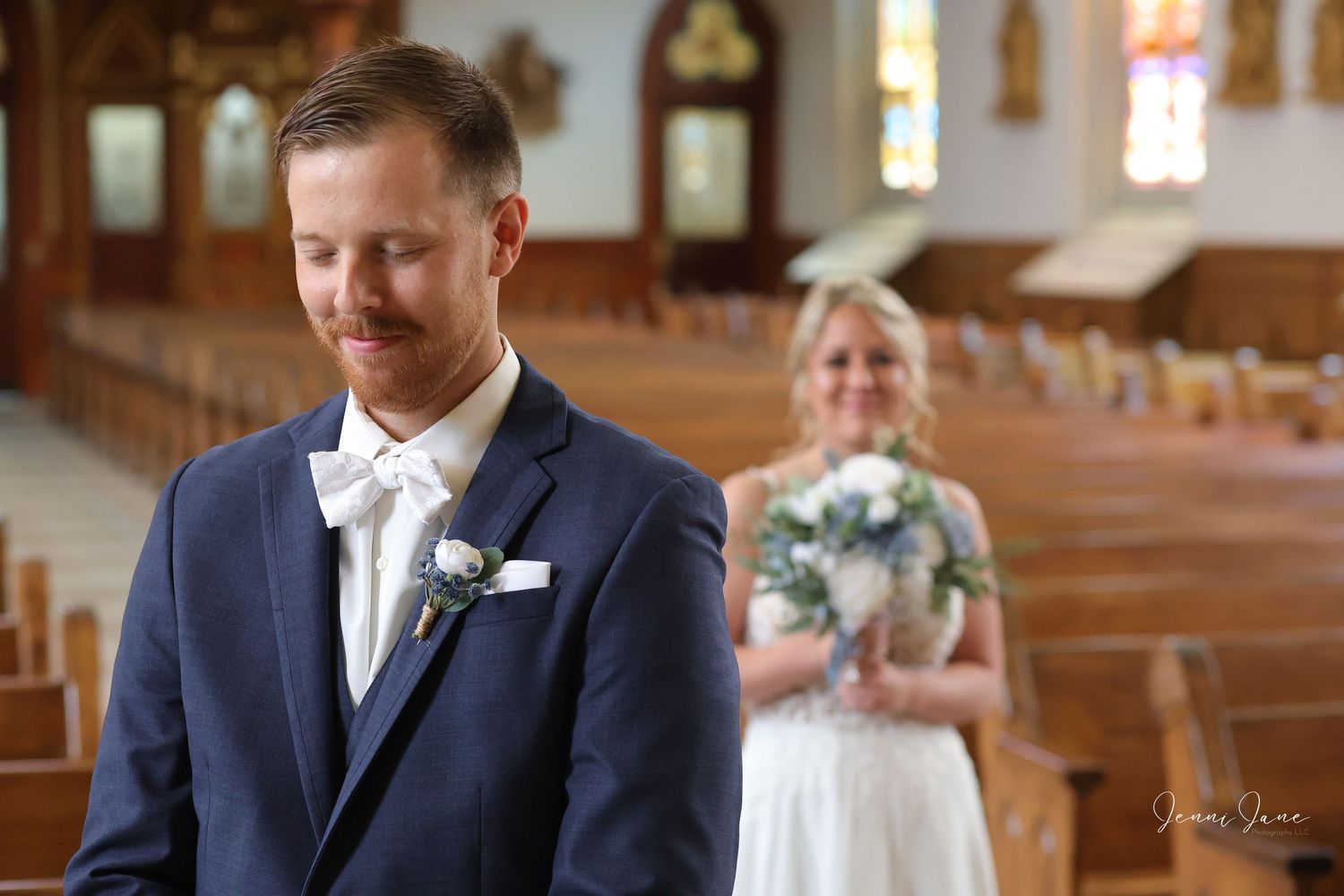 A couple shares an intimate moment during their wedding ceremony inside a beautiful church with stained glass windows.