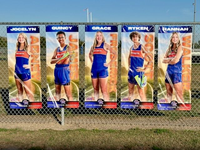Five large sports banners featuring athletes named Jocelyn, Quincy, Grace, Ryken, and Hannah displayed on a chain-link fence.