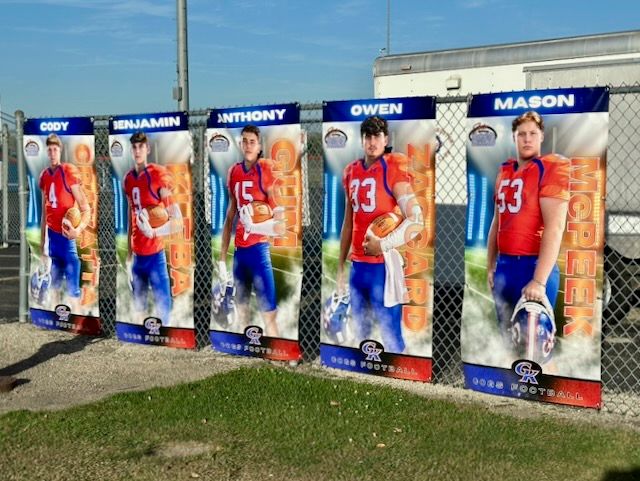 Five football player banners displaying athletes named Cody, Benjamin, Anthony, Owen, and Mason in blue and orange uniforms.