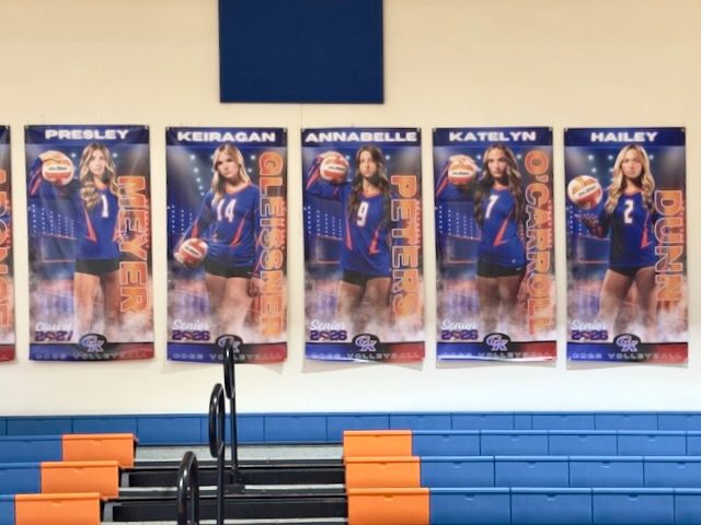 Volleyball team player banners displayed on gym wall featuring players Presley, Keiragan, Annabelle, Katelyn, and Hailey.