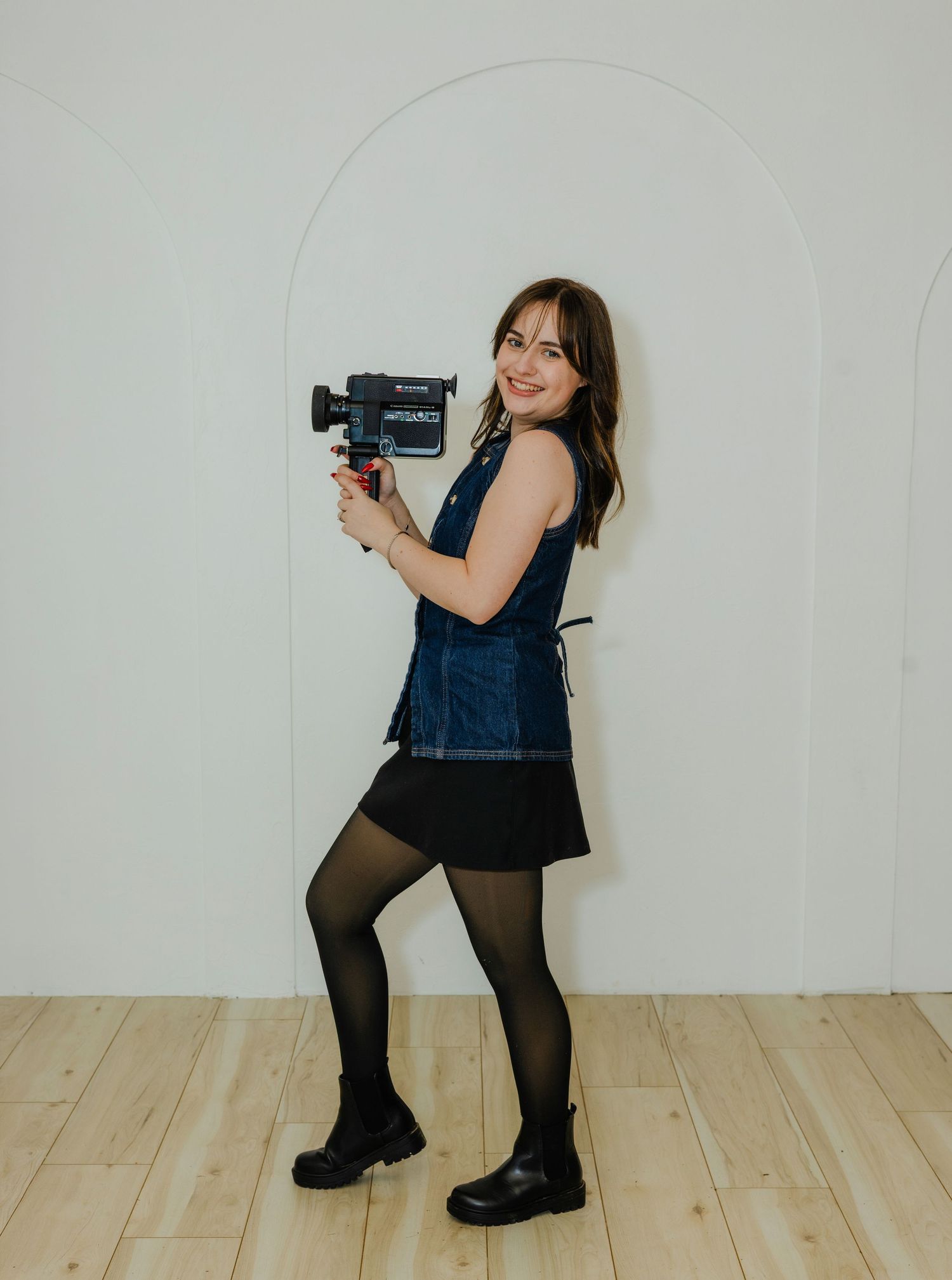 A sequence of four photos showing someone in denim overalls and black tights posing playfully against a white wall.