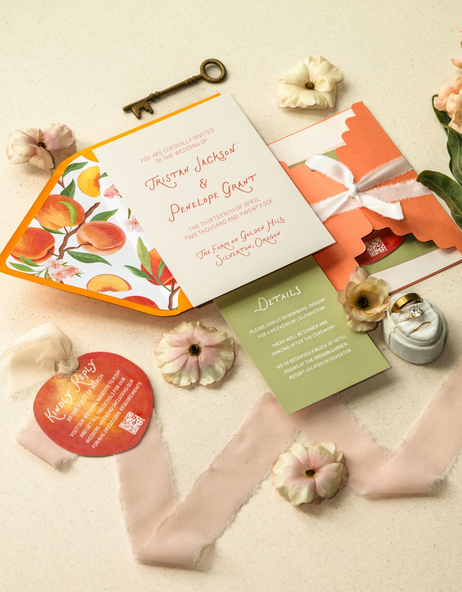 Elegant wedding invitation suite with orange floral design, green details card, ribbon, flowers, and vintage key on neutral background.