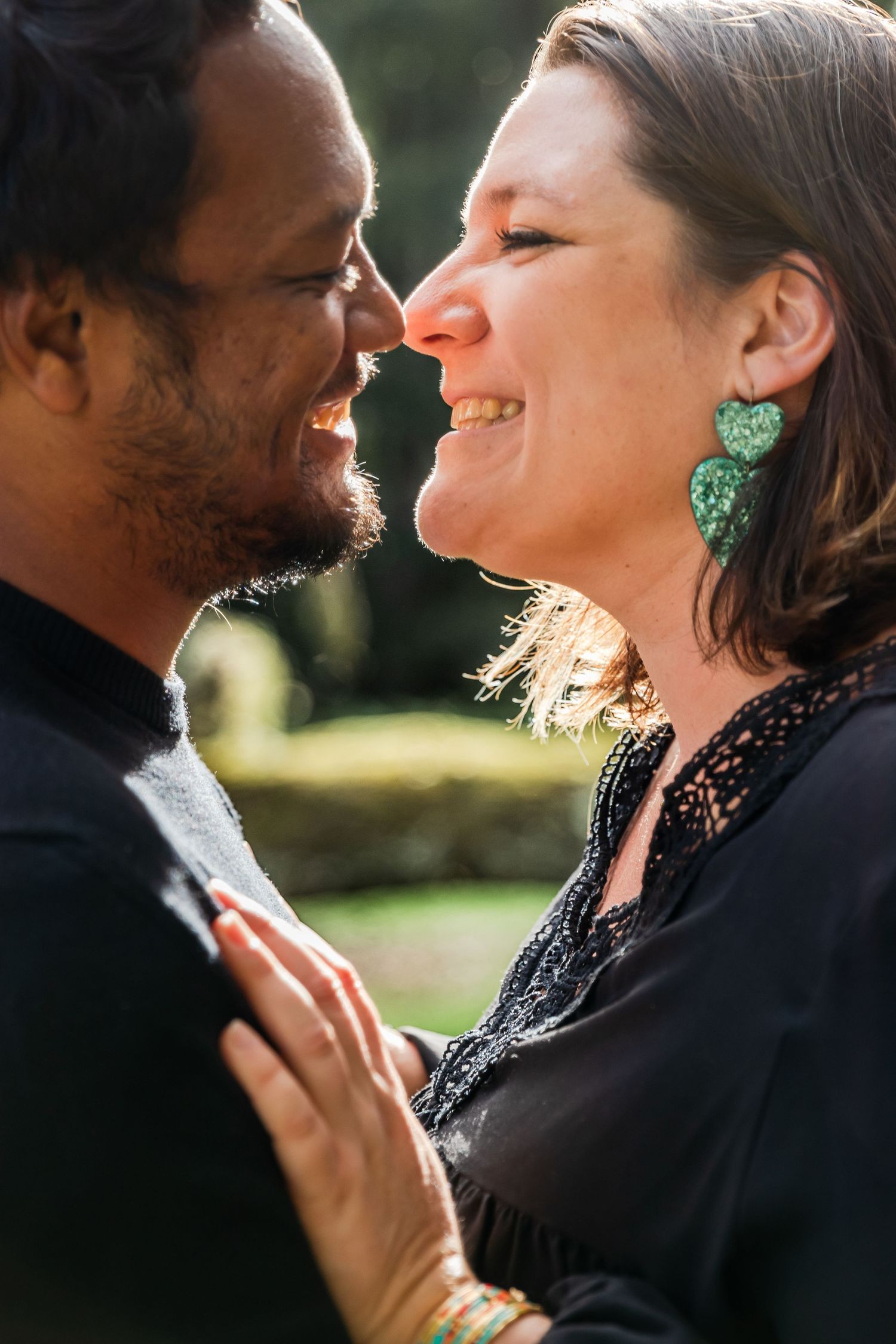 Happy interracial couple sharing a romantic moment outdoors, smiling face to face in a sunlit garden.