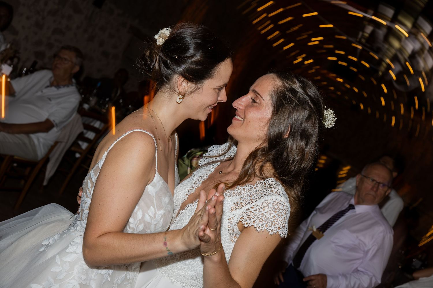 Two brides in white dresses share a joyful moment together on their wedding day.