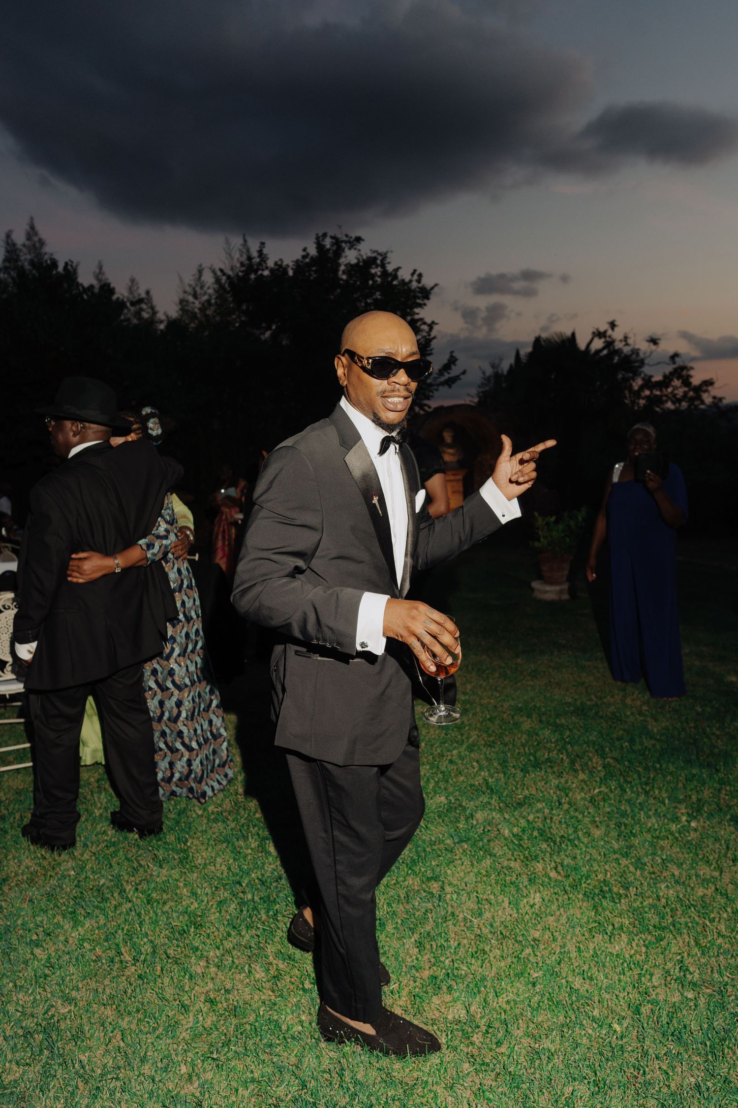 wedding guest in tuxedo tuxedo with sunglasses dancing at outdoor evening formal event.