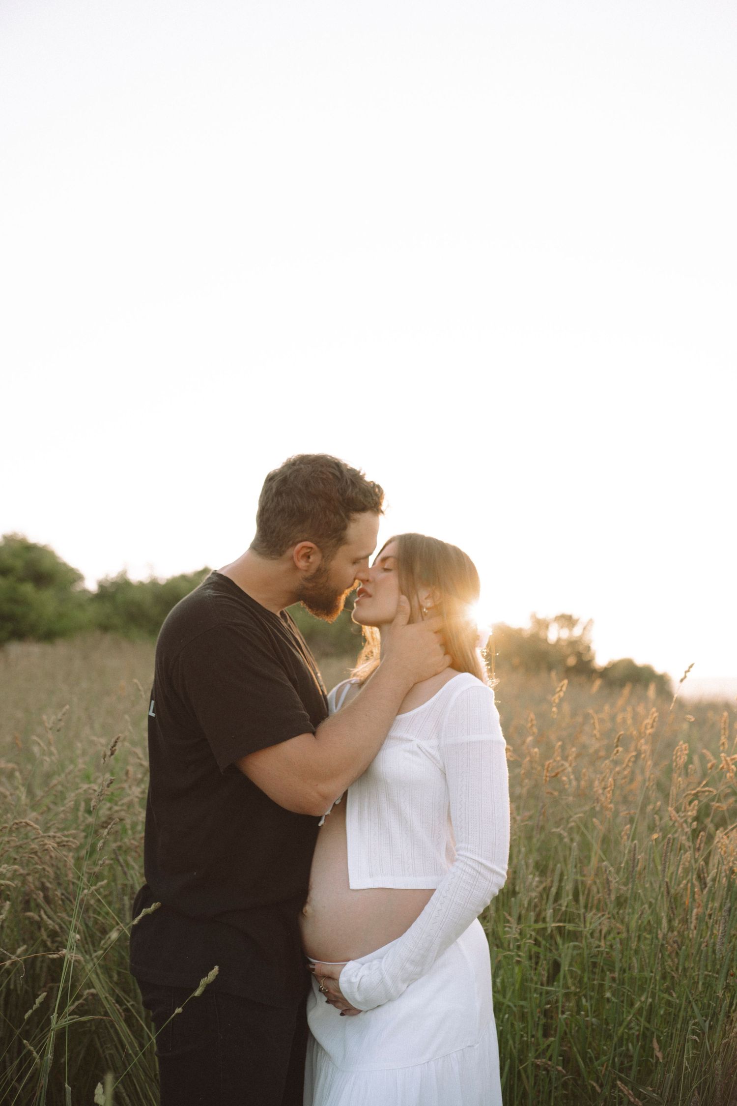 Intimate sunset portrait of expecting couple in contrasting black and white outfits.