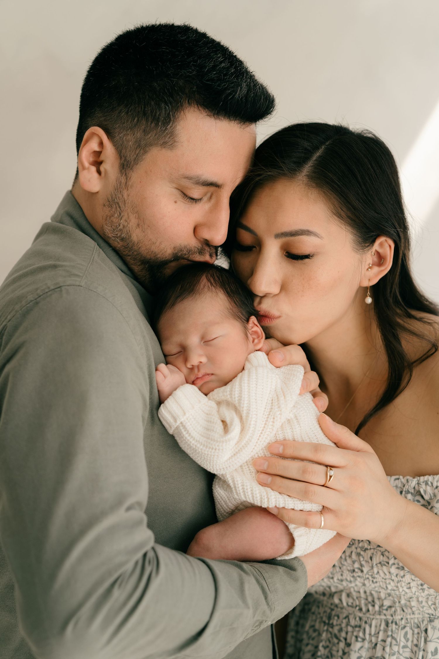 Intimate family portrait with newborn baby in soft natural light.