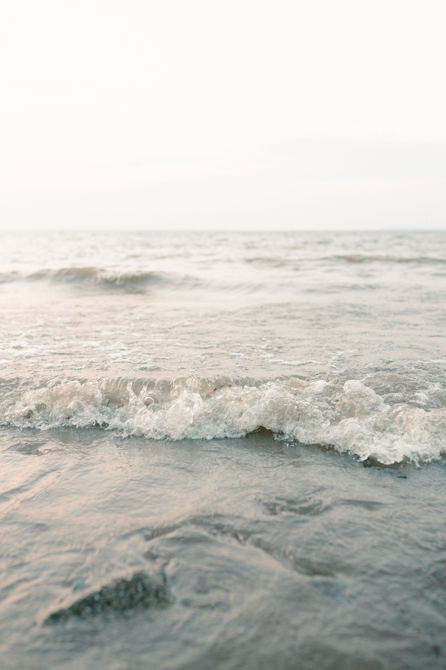 Gentle ocean waves rolling onto shore in soft, dreamy lighting.