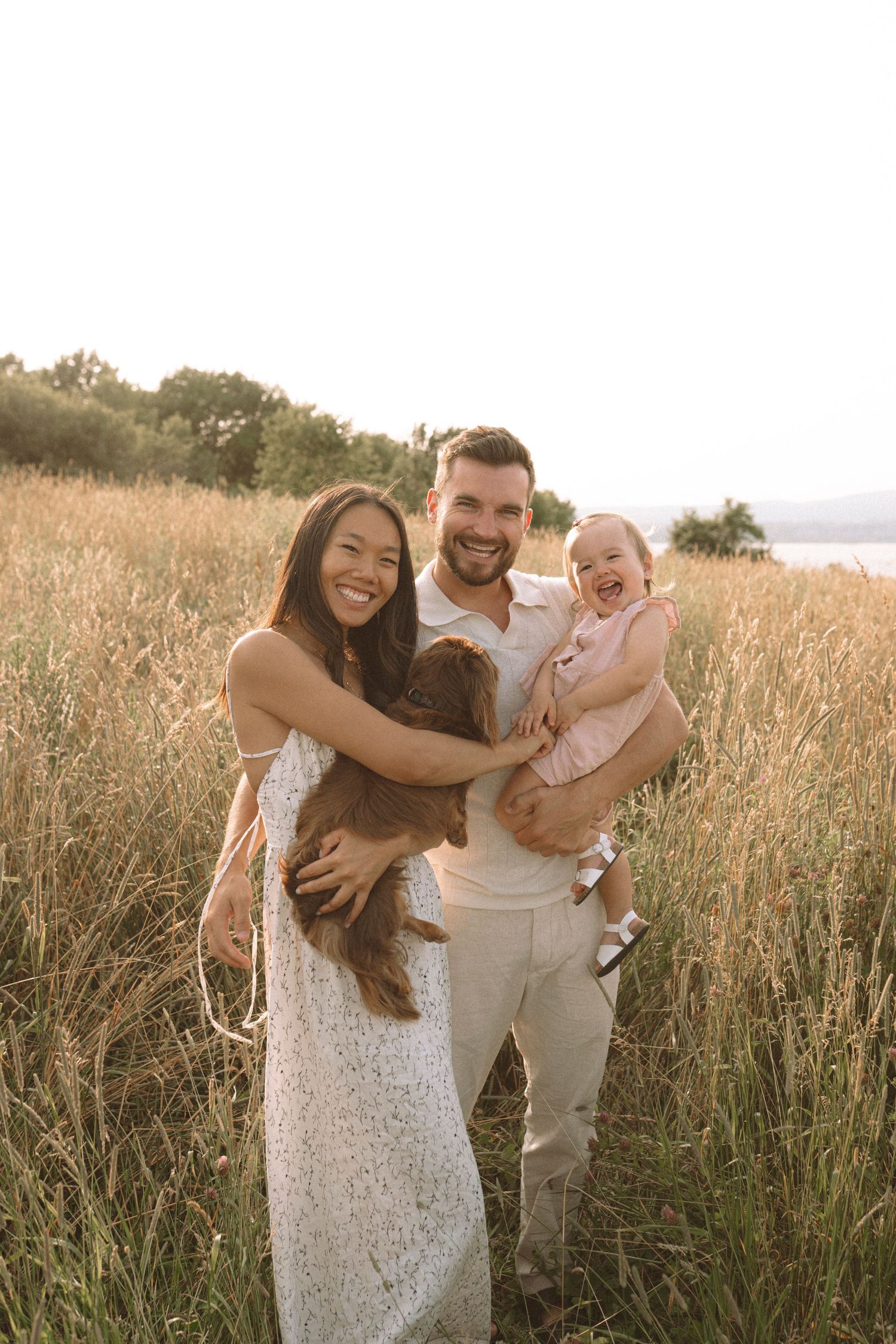 Happy family with pet dog enjoying sunset in a scenic meadow.