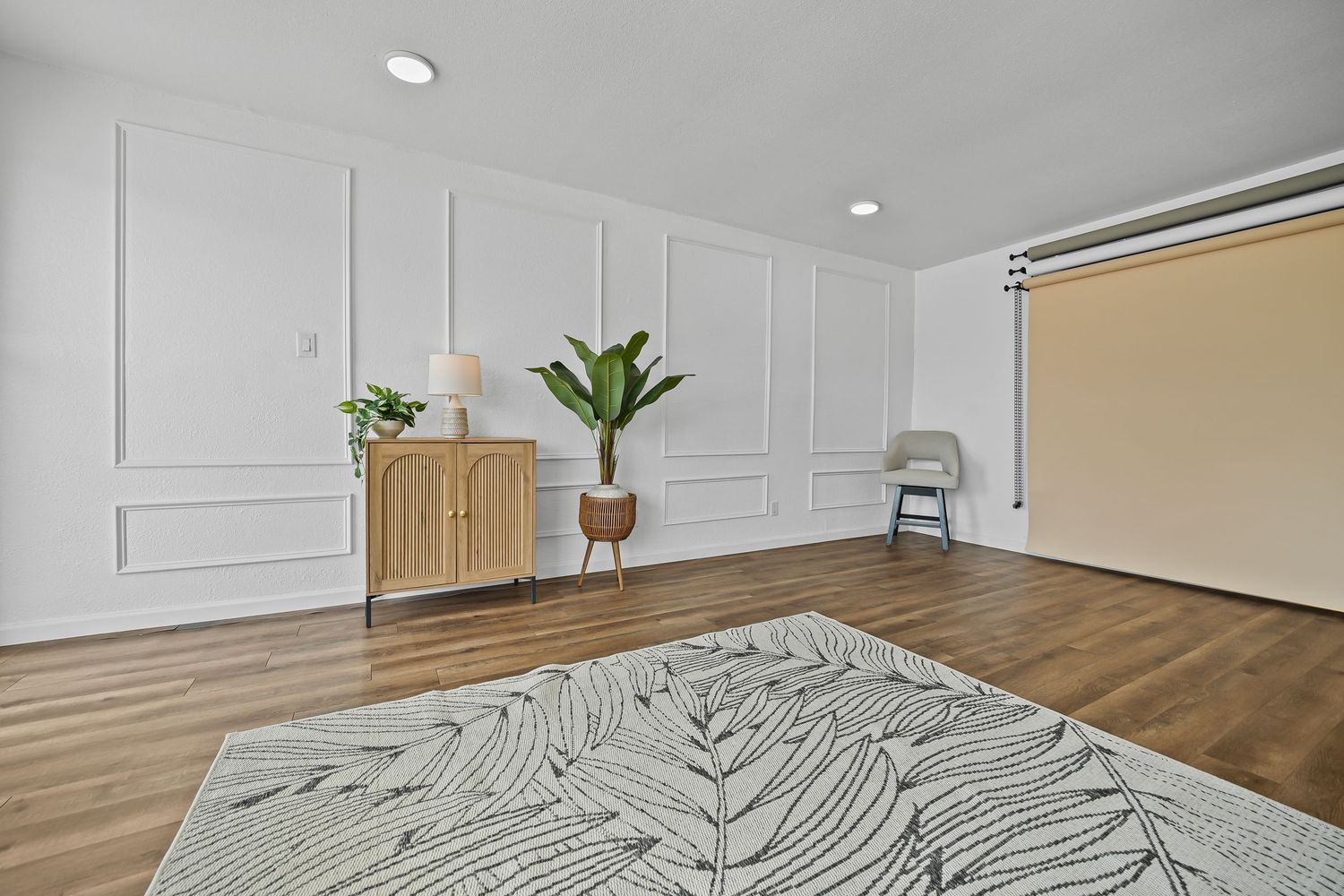 Elegant living space featuring wicker cabinet, tall plant, decorative wainscoting wall panels, and patterned area rug.