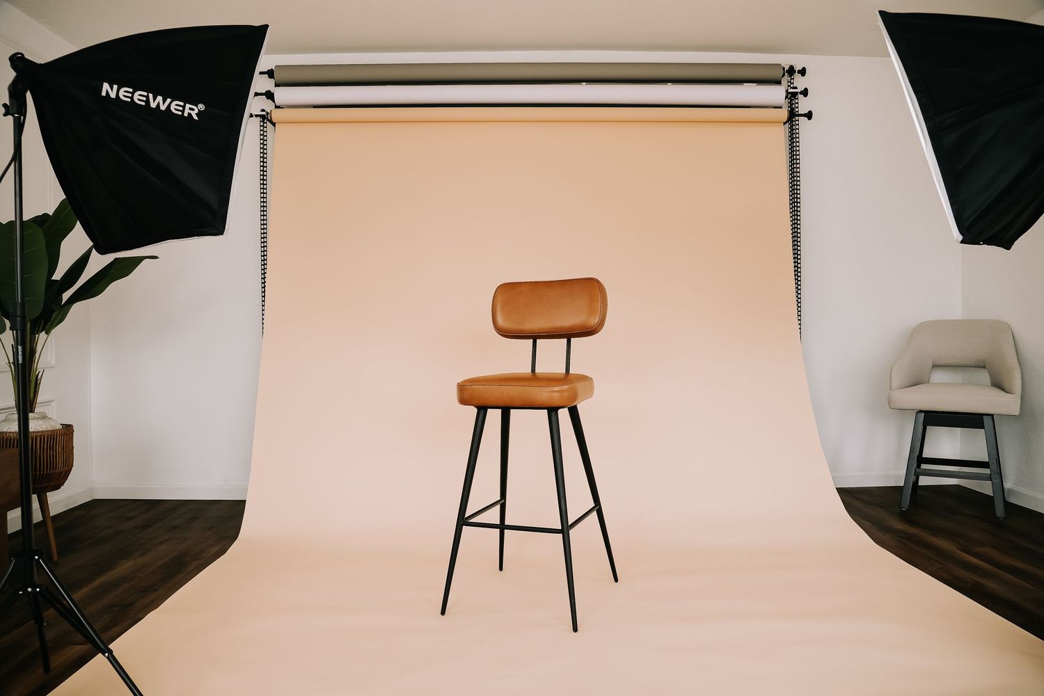 Brown leather bar stool on black metal legs centered against a cream backdrop in a professional photo studio.