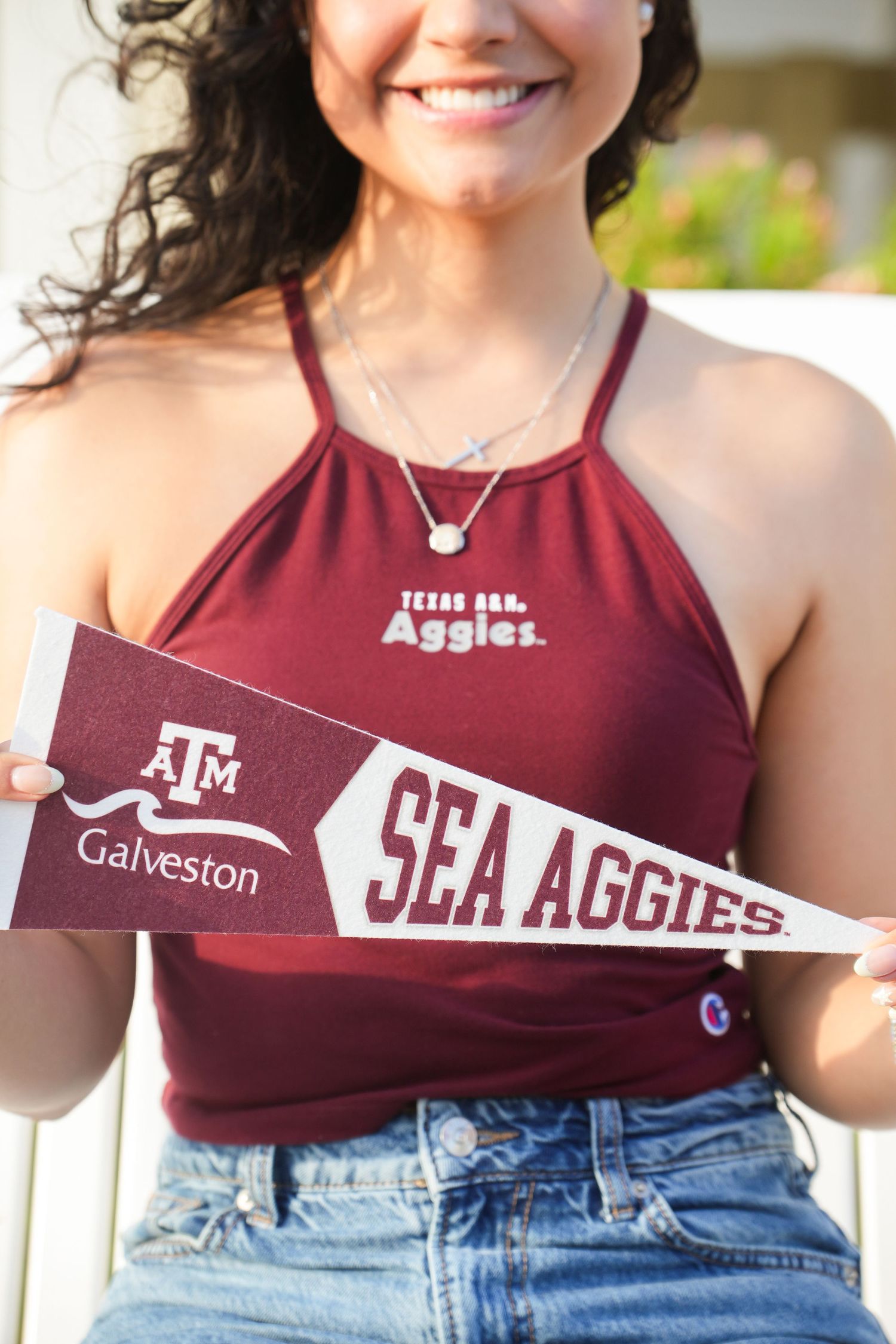 Young woman in maroon Texas A&M Aggies top holds a Texas A&M Galveston Sea Aggies pennant flag.