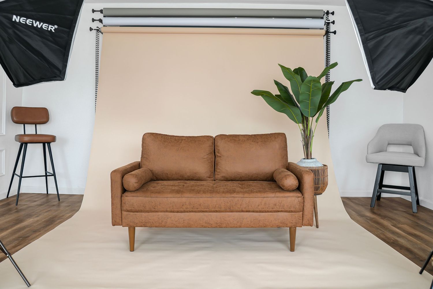 Caramel brown leather loveseat with wooden legs photographed in professional studio with softbox lighting.
