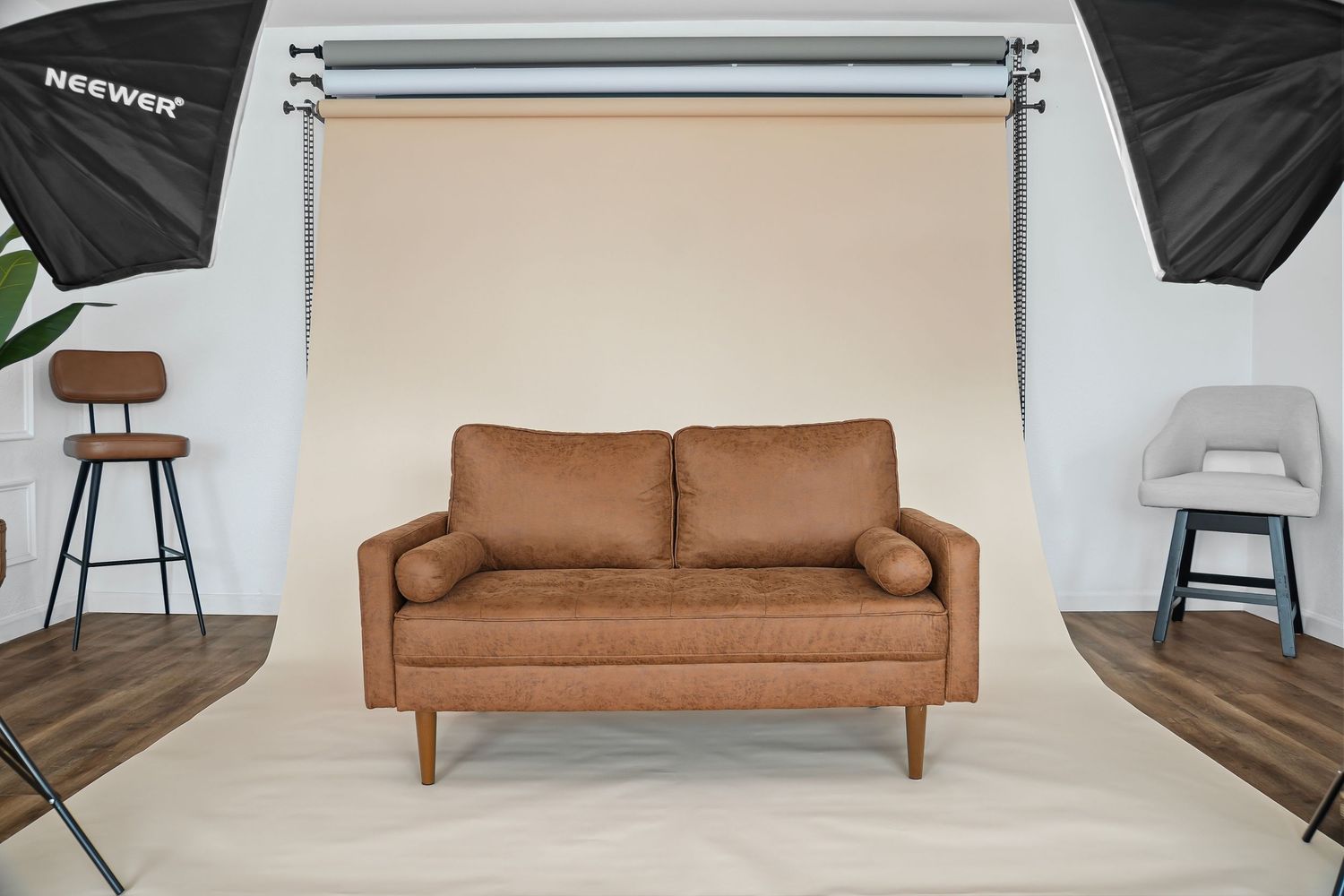 Tan leather mid-century modern loveseat on white backdrop in professional product photography studio.
