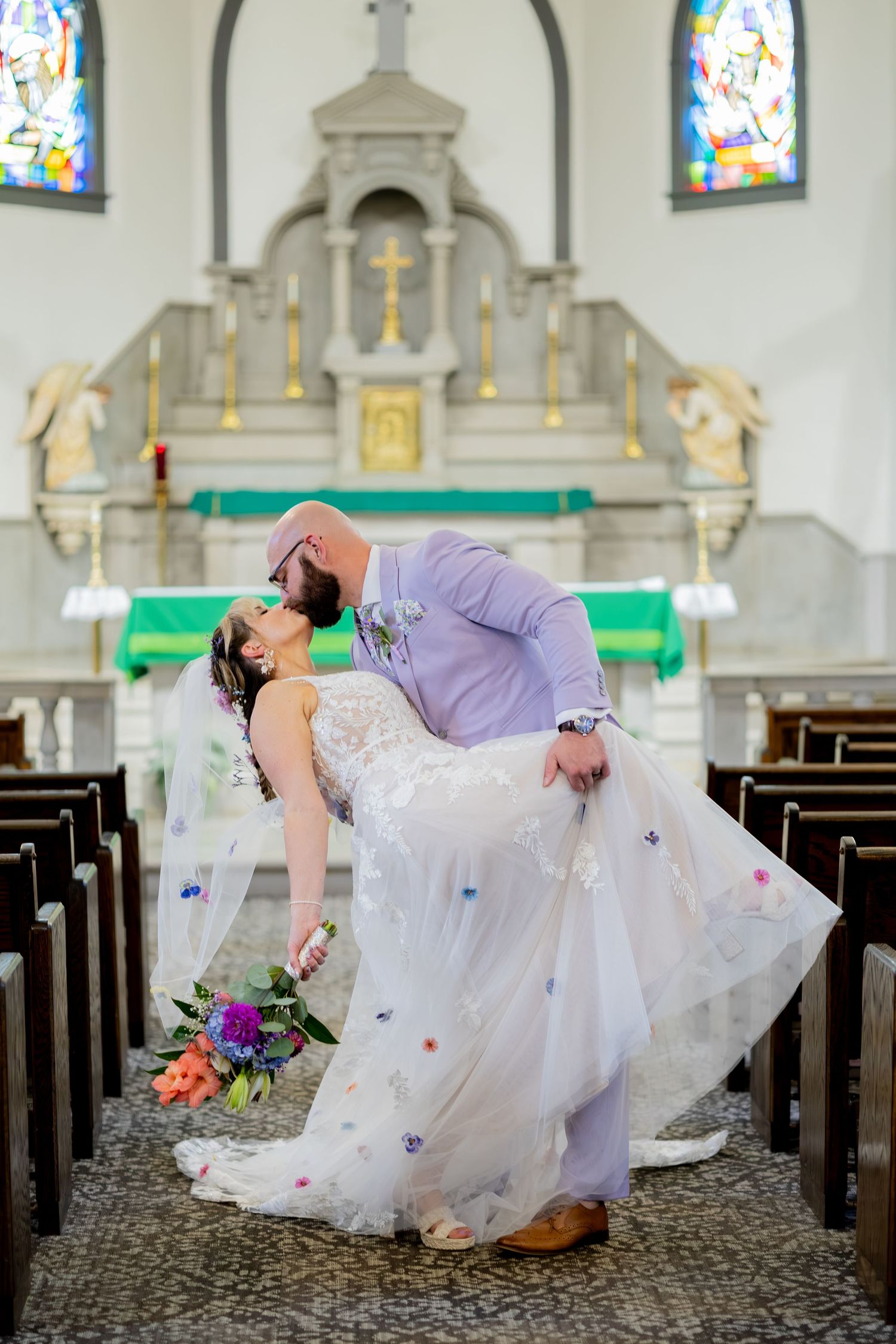 Newly married couple share a joyful kiss in the church aisle after their ceremony.