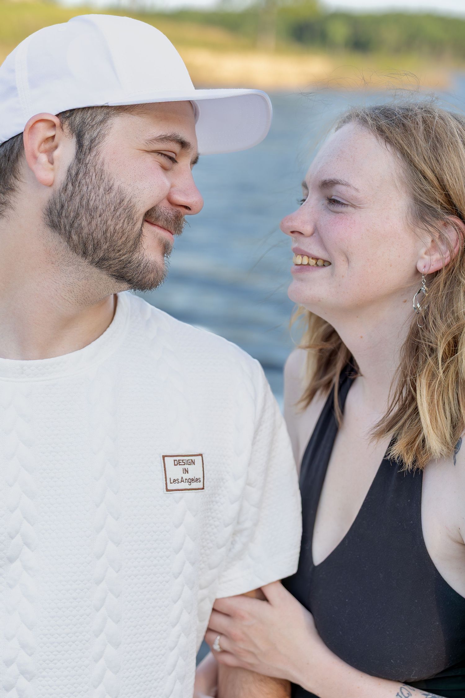 Engaged couple sharing romantic moments during an outdoor engagement session with natural posing, genuine smiles, and golden-hour light.