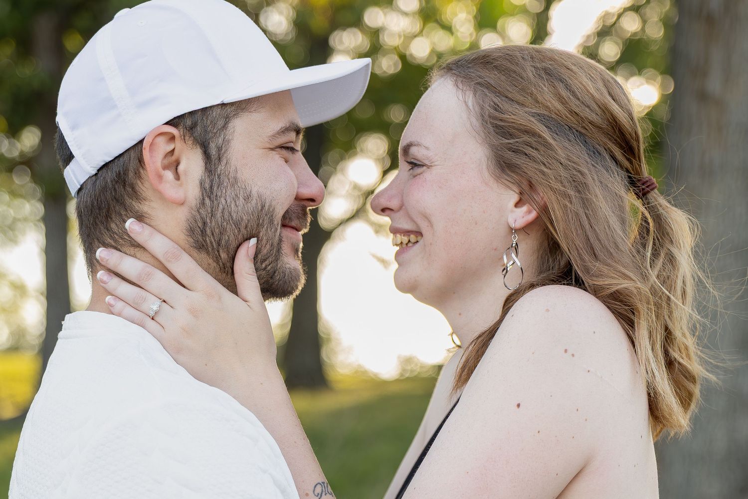 Engaged couple sharing romantic moments during an outdoor engagement session with natural posing, genuine smiles, and golden-hour light.