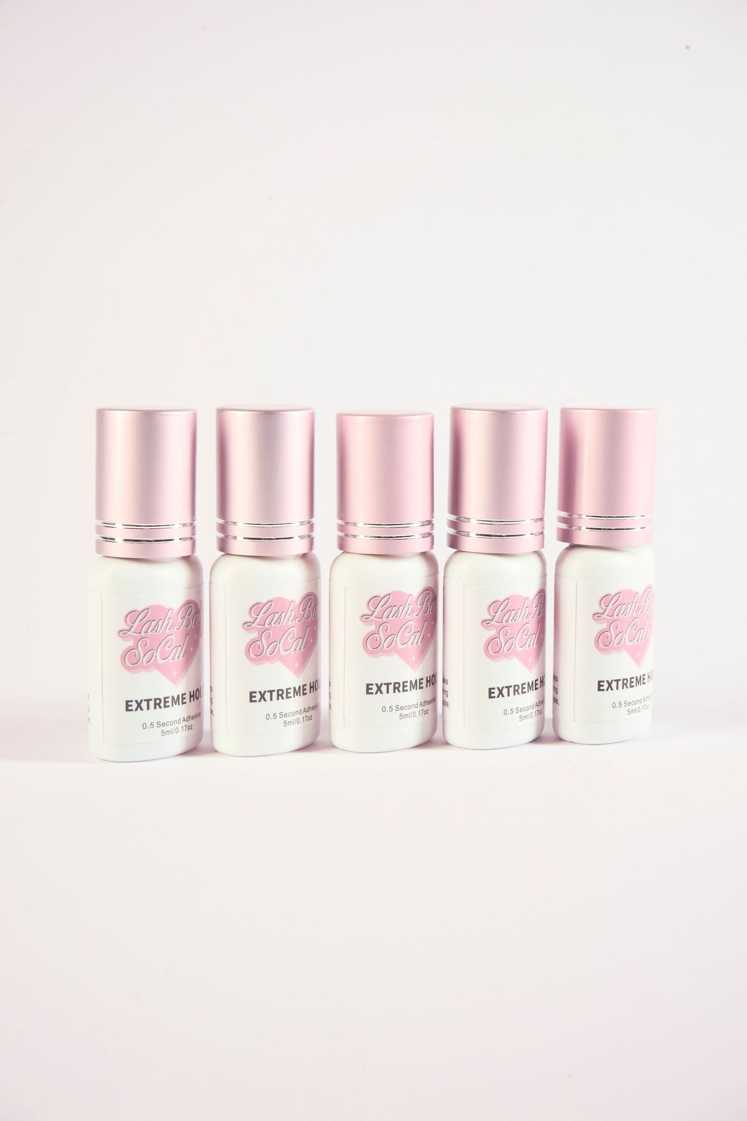 Five pink-capped Extreme Hold mini bottles arranged in a row on a pink background.