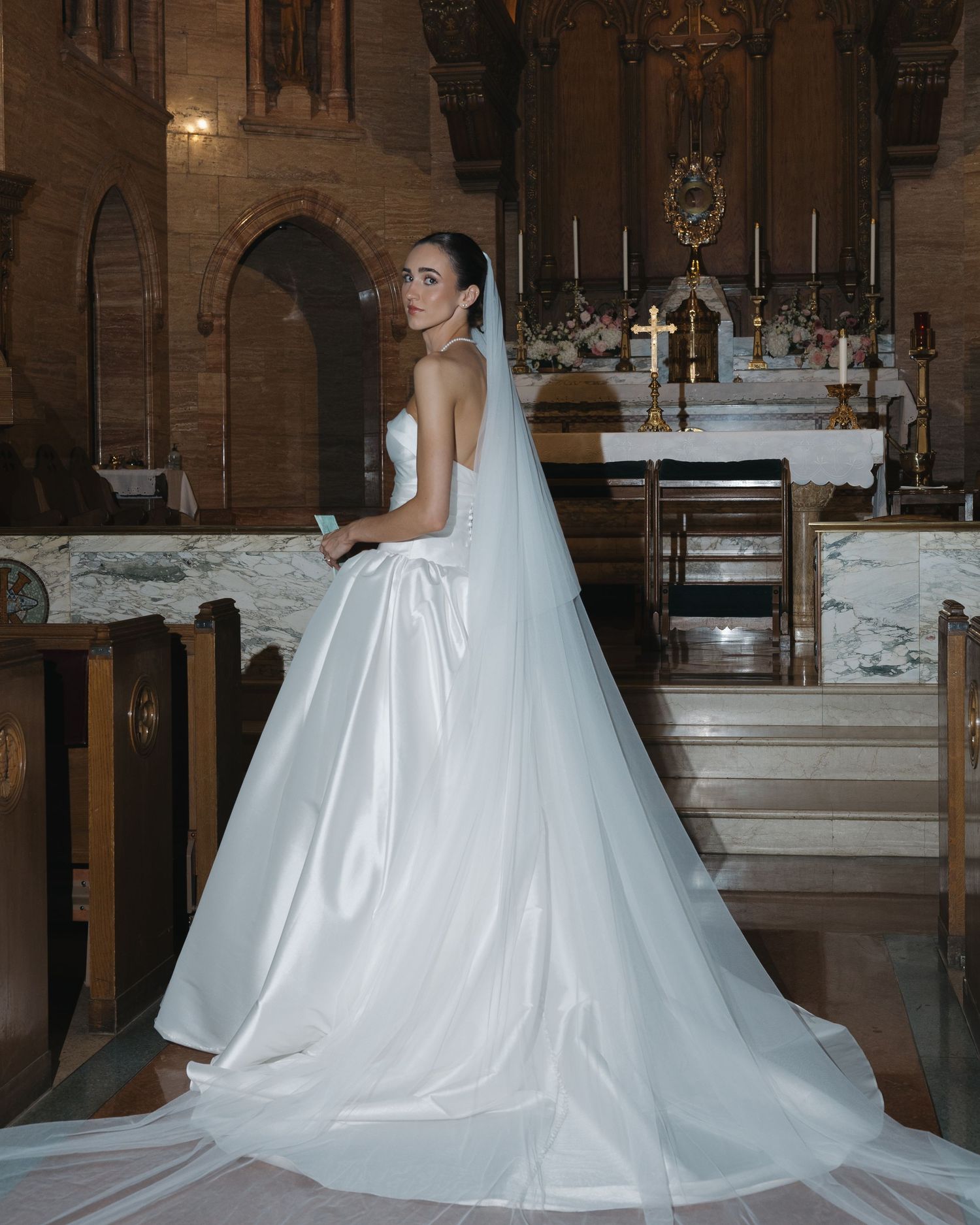 Bride wearing an elegant white wedding gown and veil inside a historic church