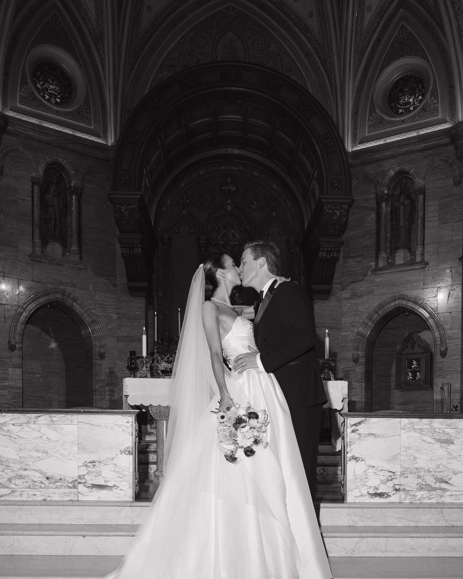 Bride and groom sharing first kiss at the altar of a stunning stone church.
