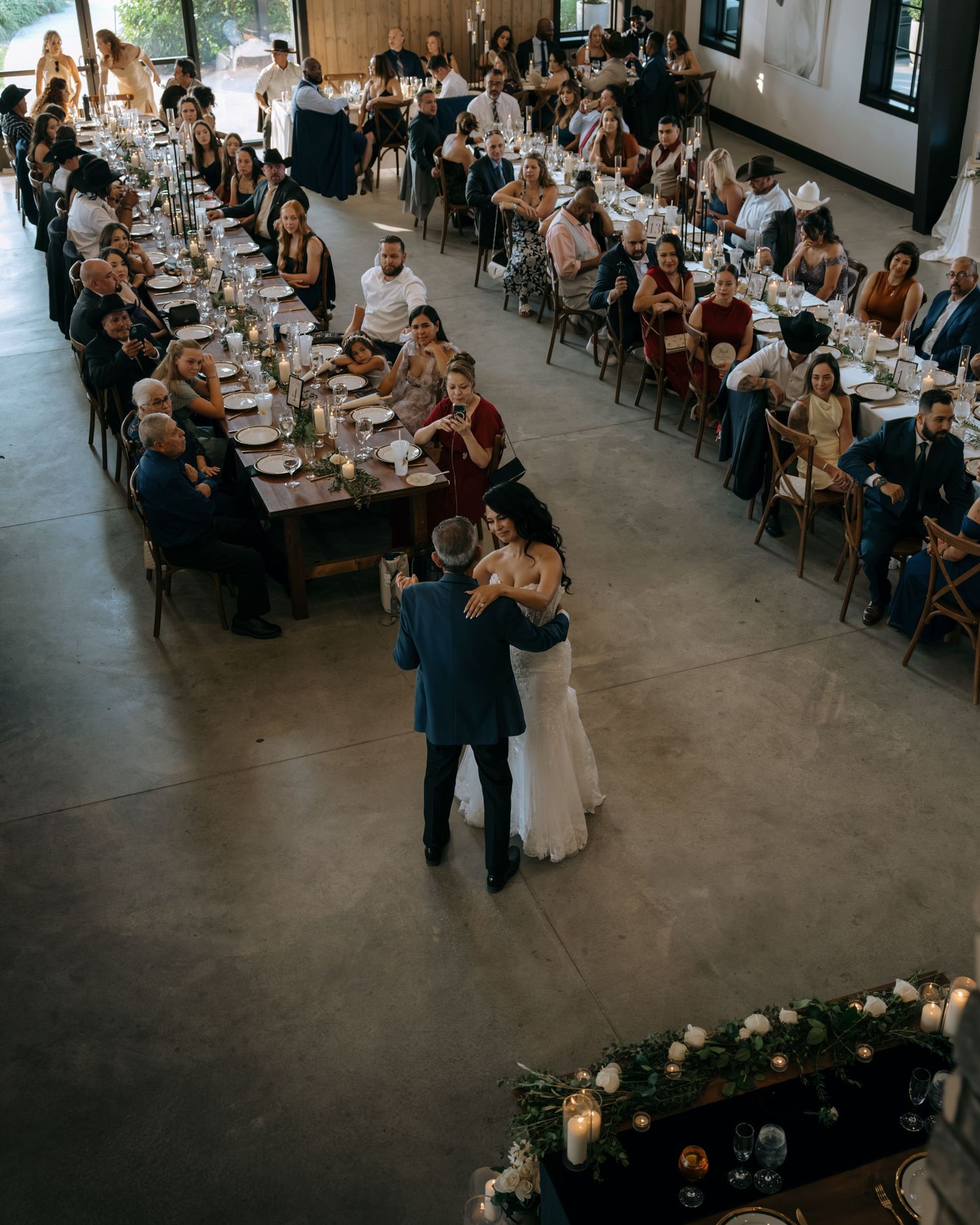 Aerial view of bride and groom sharing first dance surrounded by seated wedding guests.
