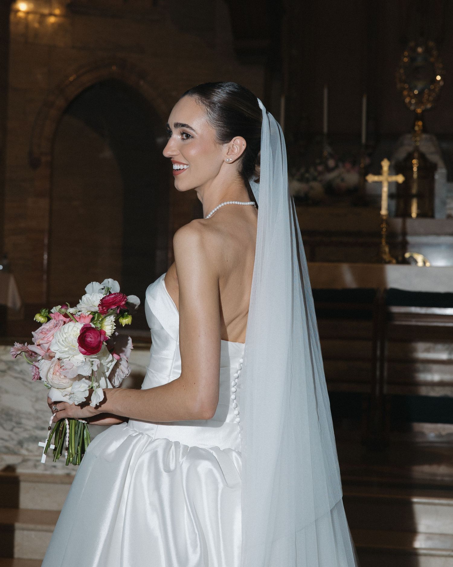 Bride holding a white floral bouquet inside a traditional Catholic church