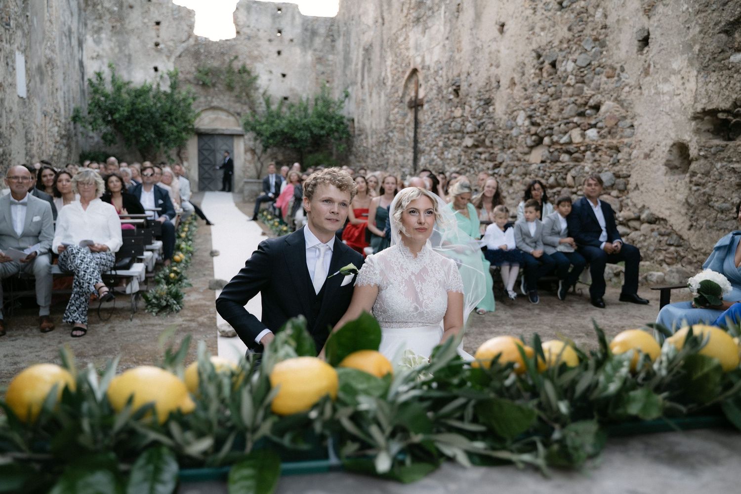 Bride and groom seated before lemon and olive branch decorations