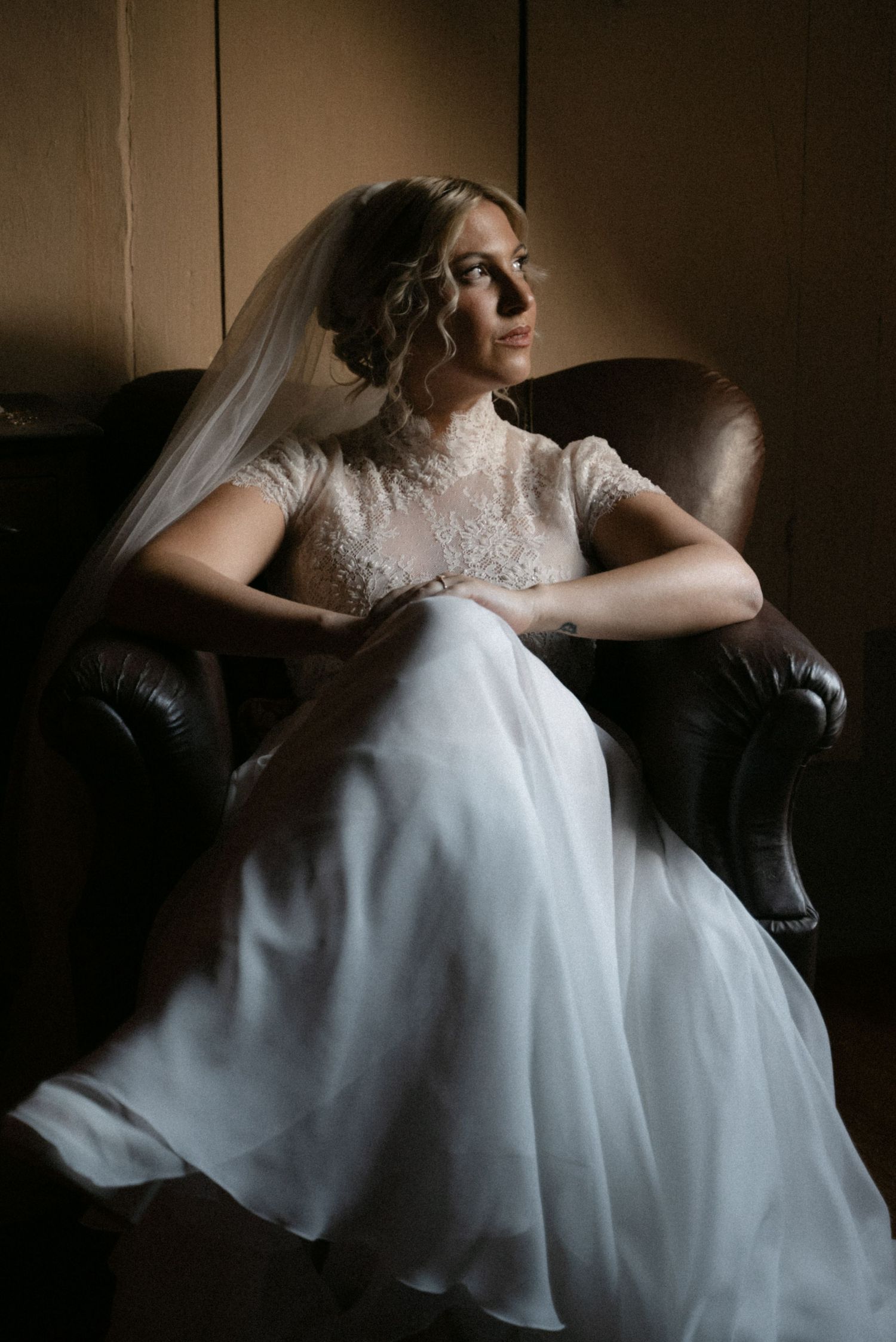 Bride seated in a leather armchair before the ceremony
