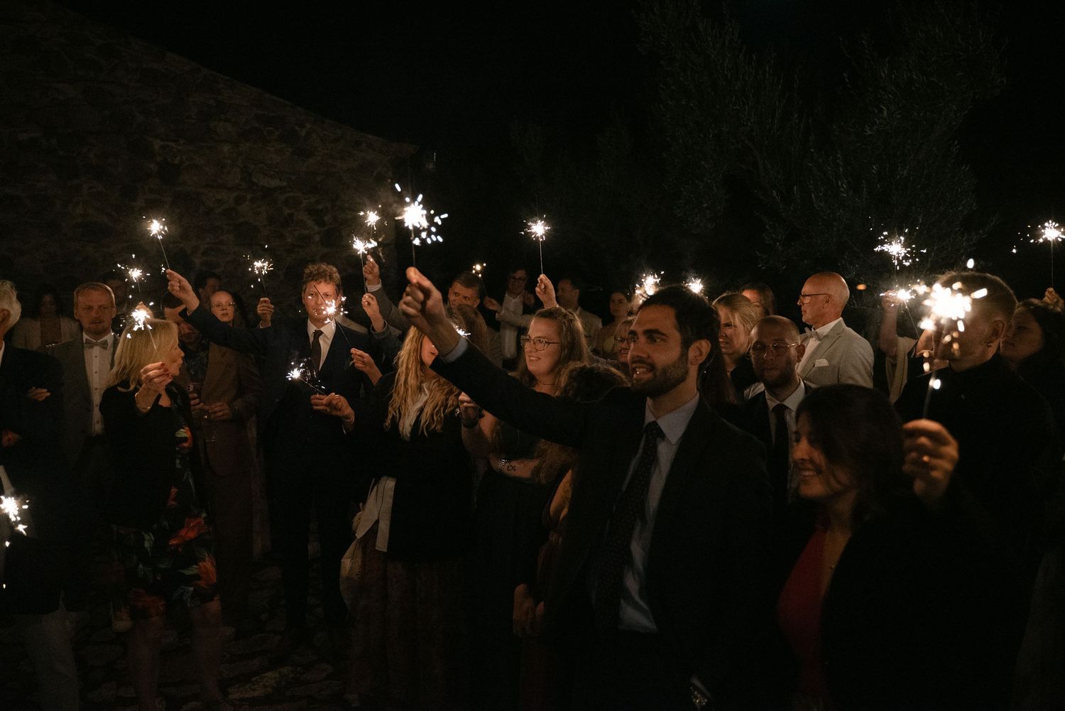 International wedding guests holding sparklers during the evening celebration