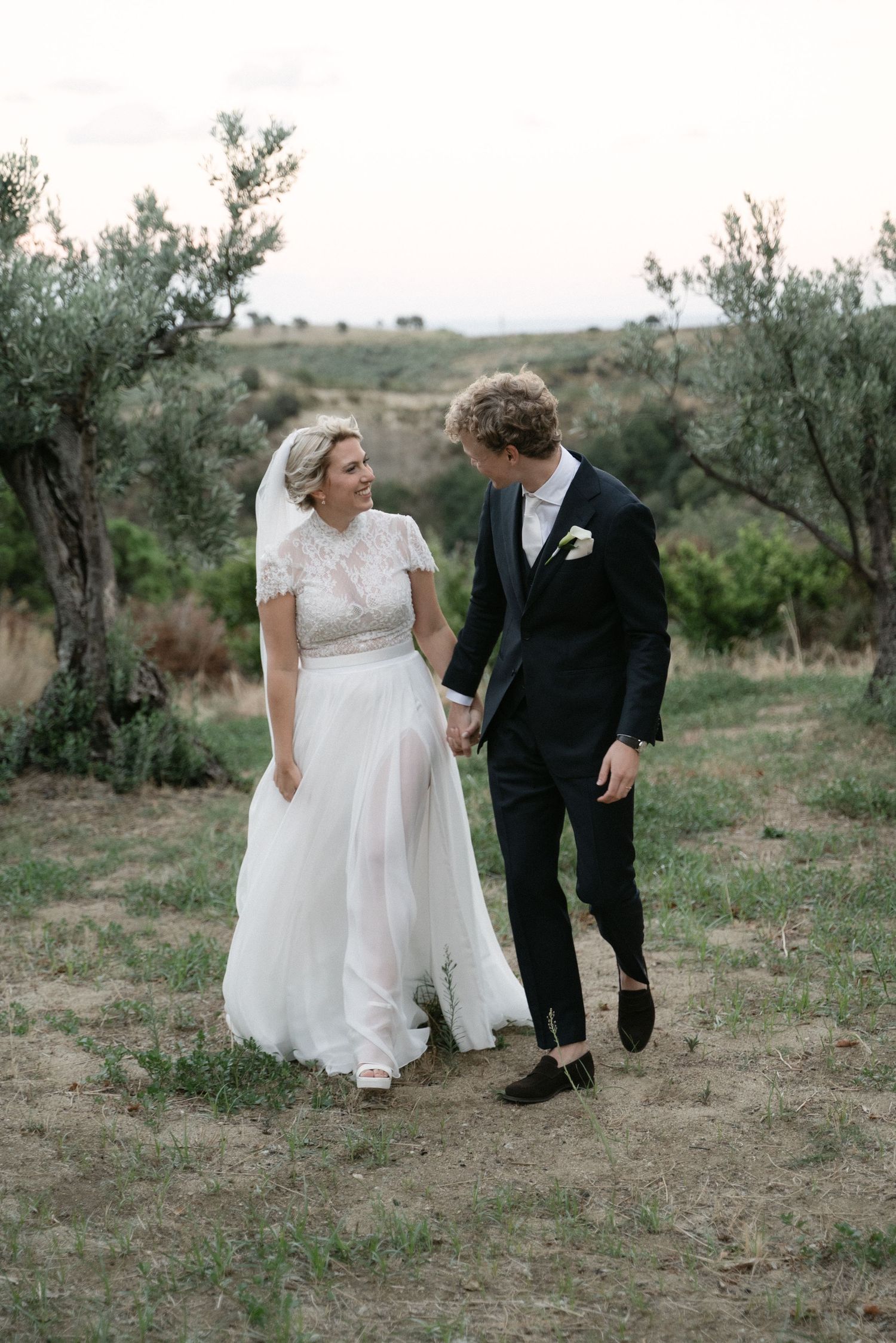 Newlyweds walking through olive trees at Borgo del Convento