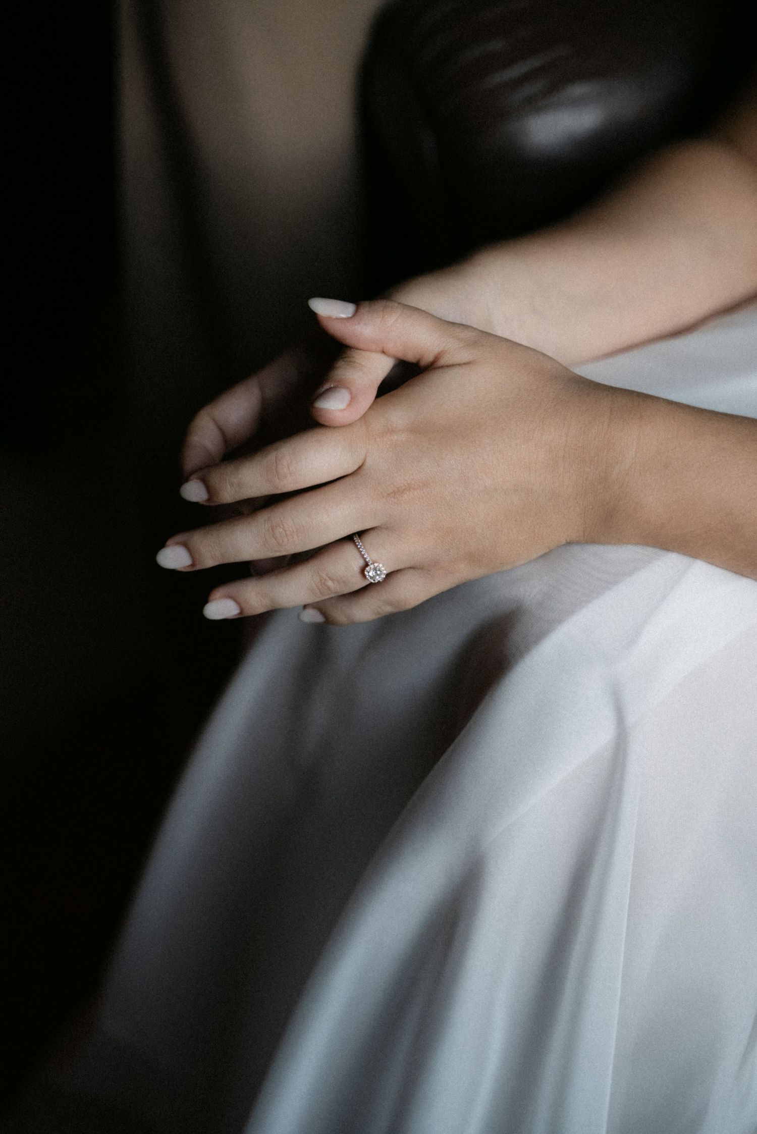 Close-up of the bride's engagement ring and wedding dress