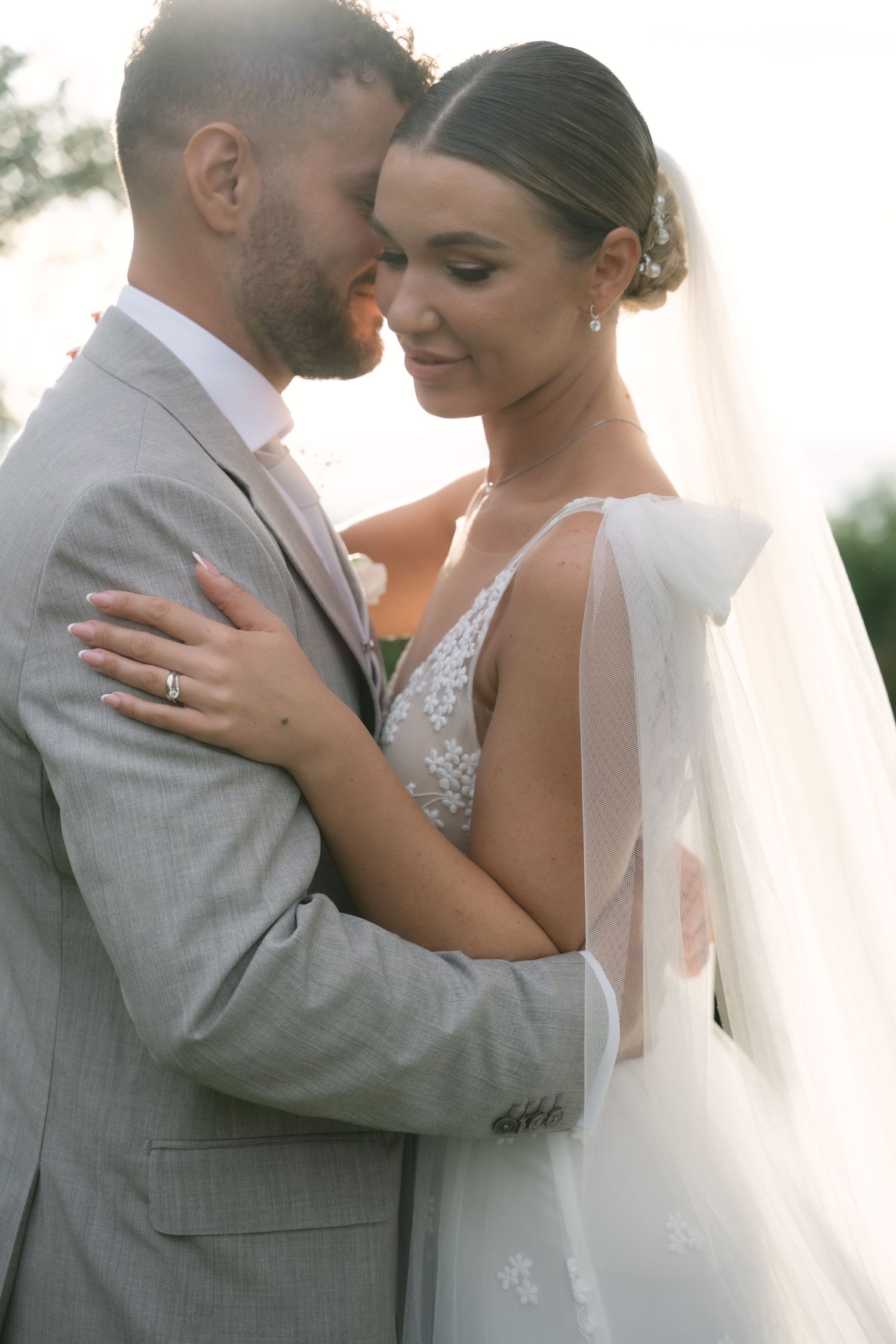 Close wedding portrait of the newlyweds in soft backlight