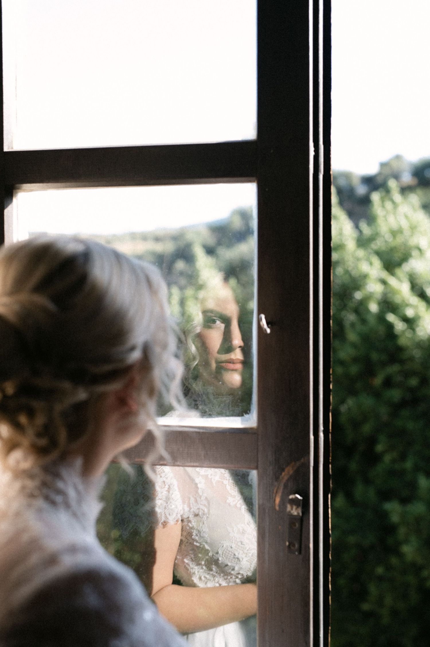 Quiet bridal moment reflected in a window before the ceremony