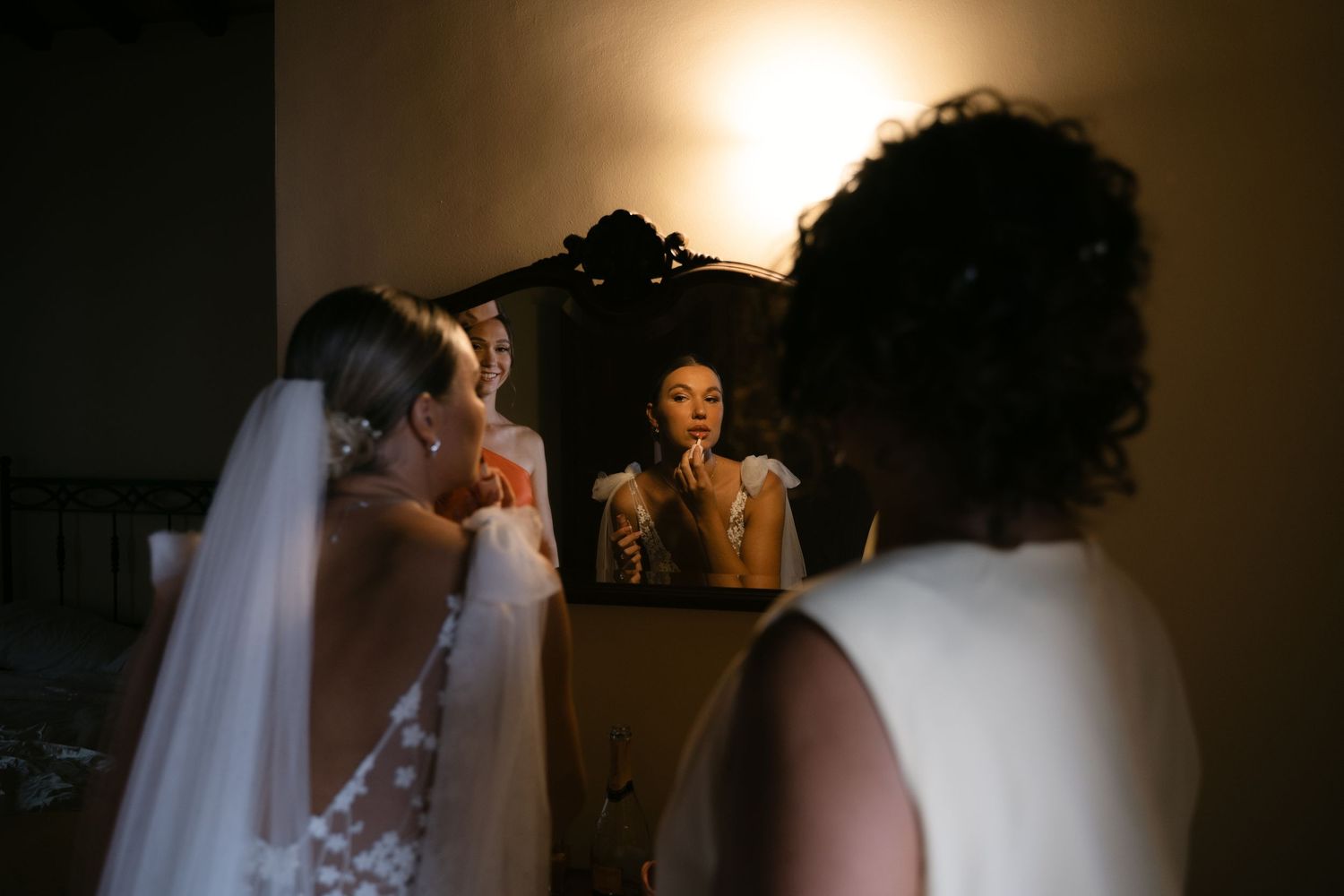 Bride applying lipstick in the mirror during wedding preparations