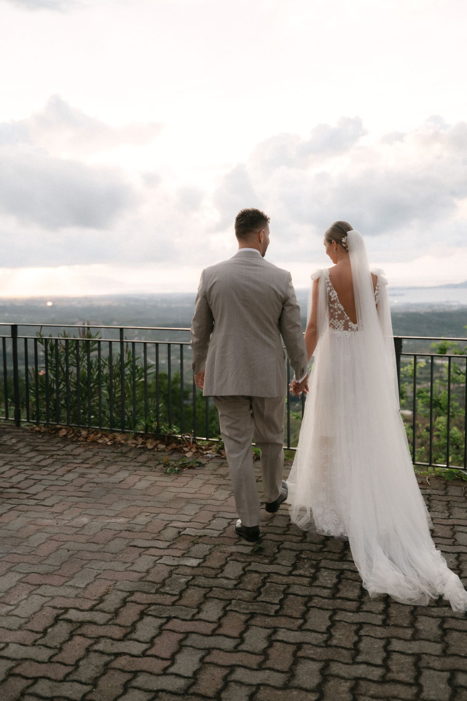 Newlyweds walking toward a panoramic viewpoint at sunset