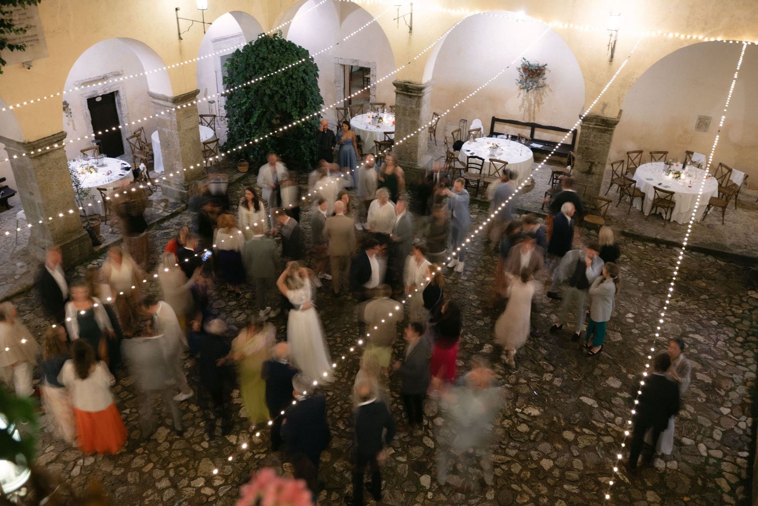 Wedding reception seen from above beneath warm string lights