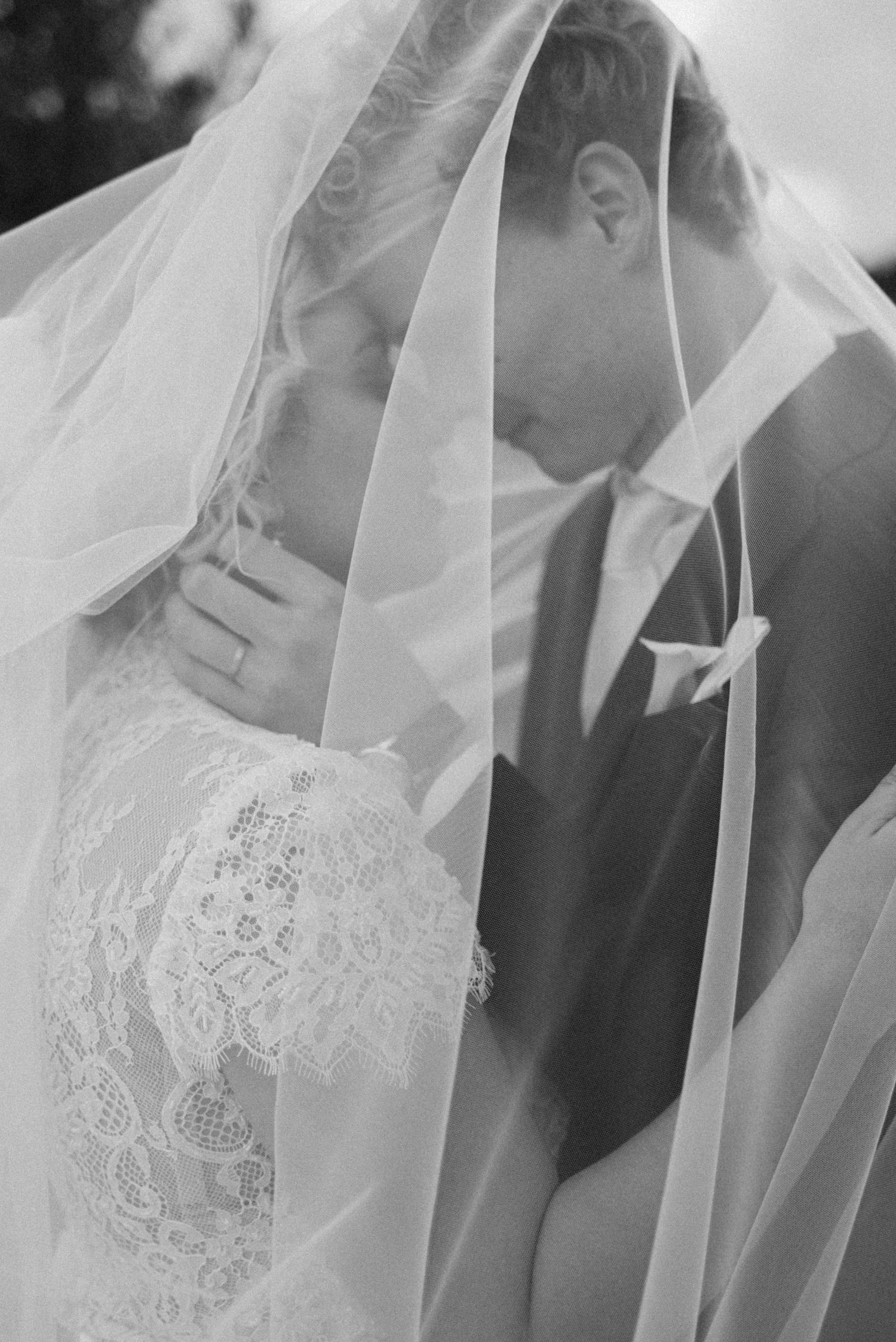 Black and white portrait of the couple beneath the wedding veil