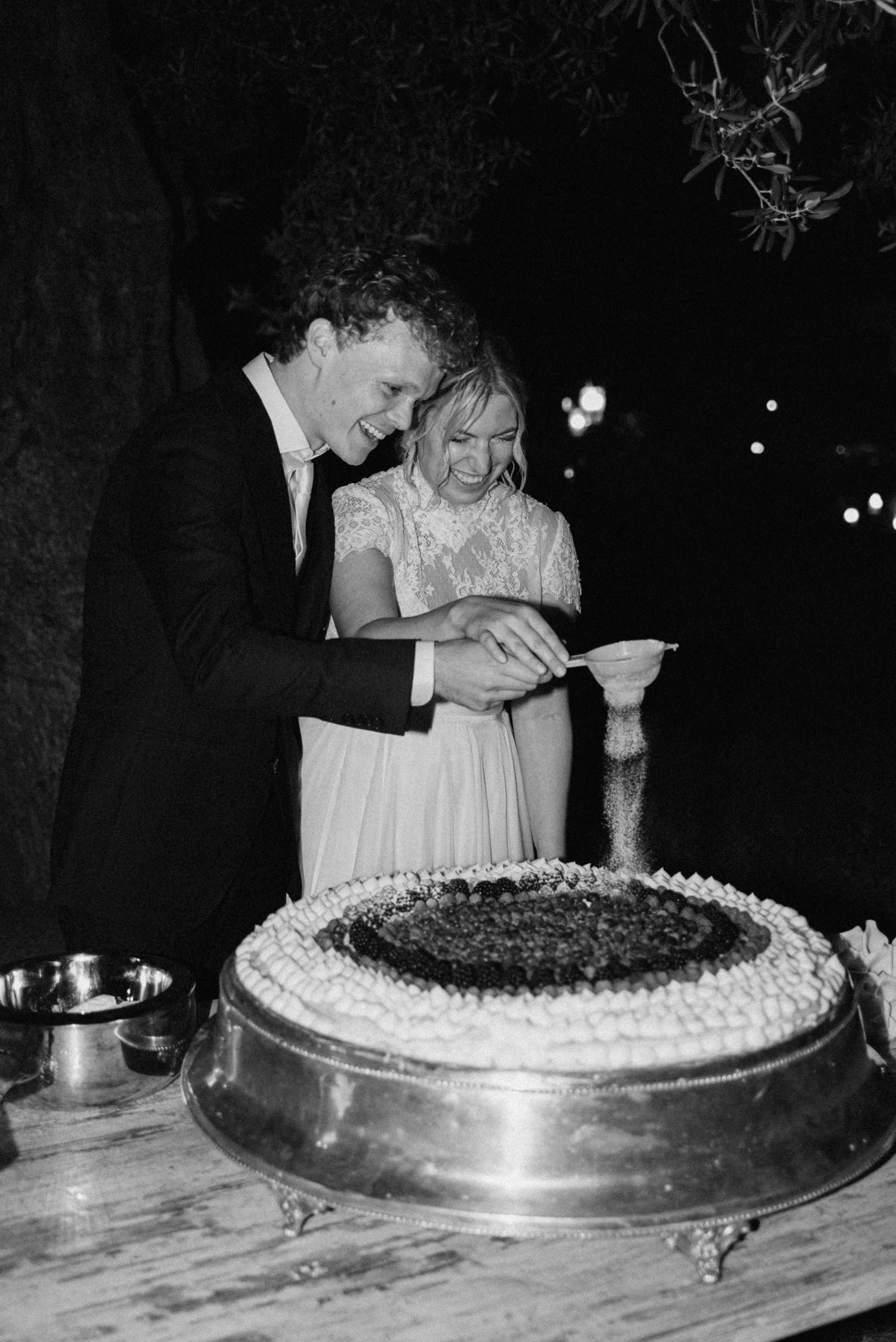 Serena and Paul cutting their wedding cake at night