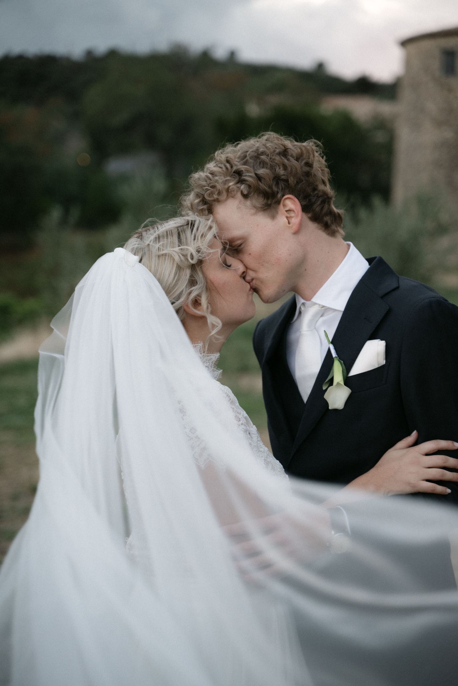 Bride and groom kissing beneath a flowing wedding veil