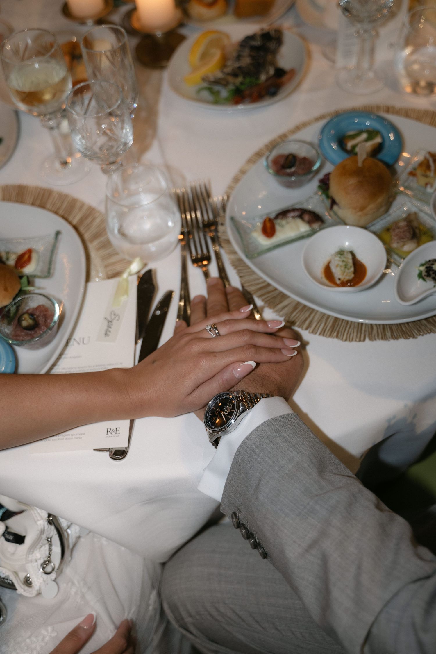 Newlyweds holding hands at the dinner table during their Sicily wedding