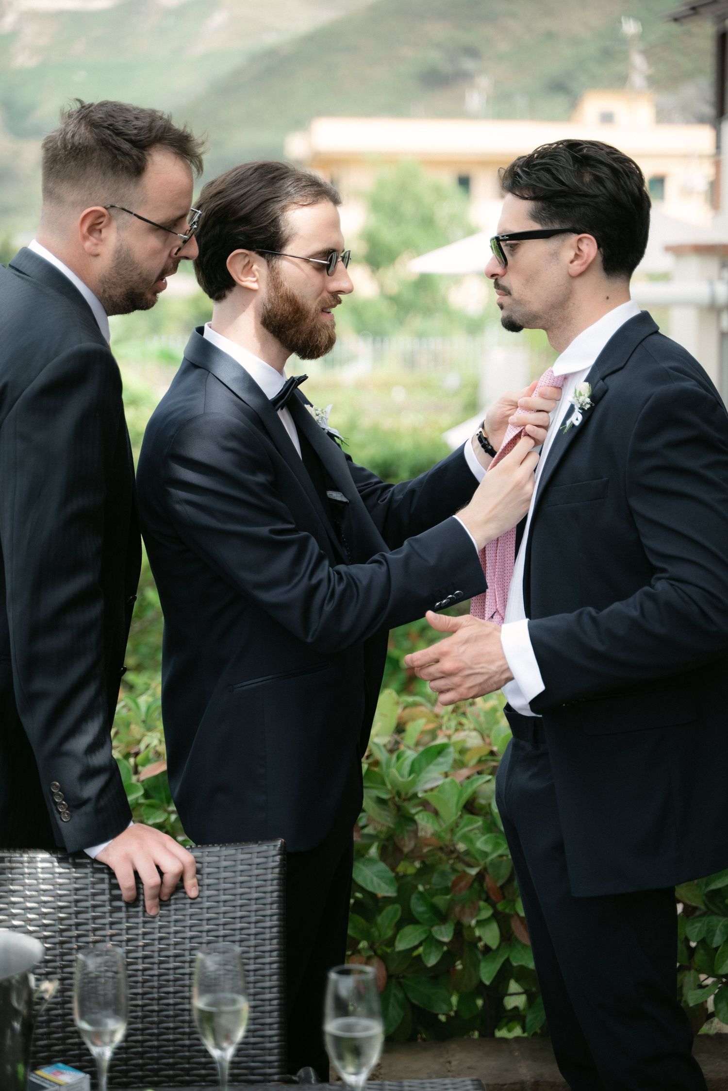 Groom helping a friend adjust his tie before the wedding