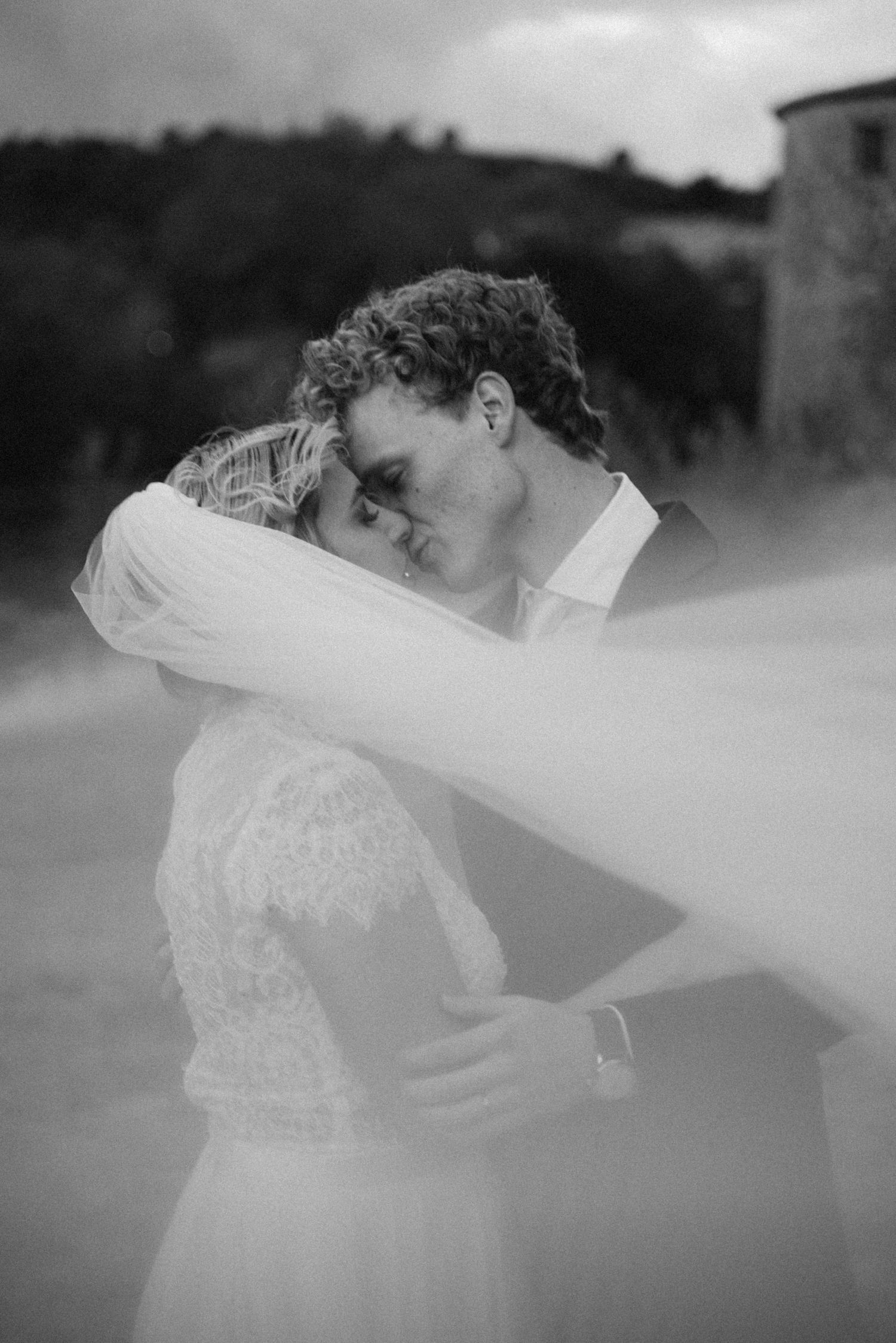 Black and white wedding portrait framed by the bride's veil