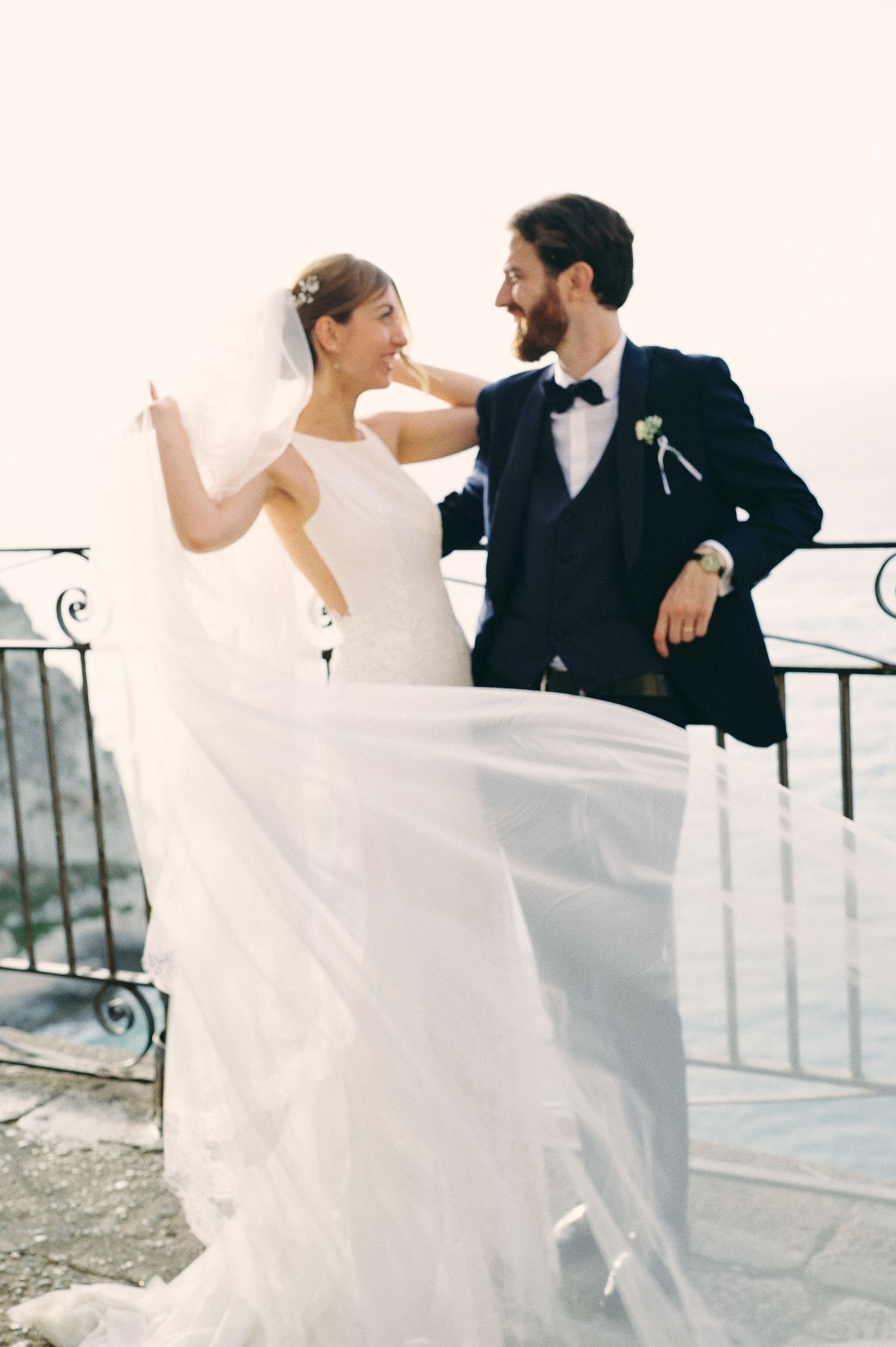 Giulia and Metz beside the sea with the bride's veil moving in the wind