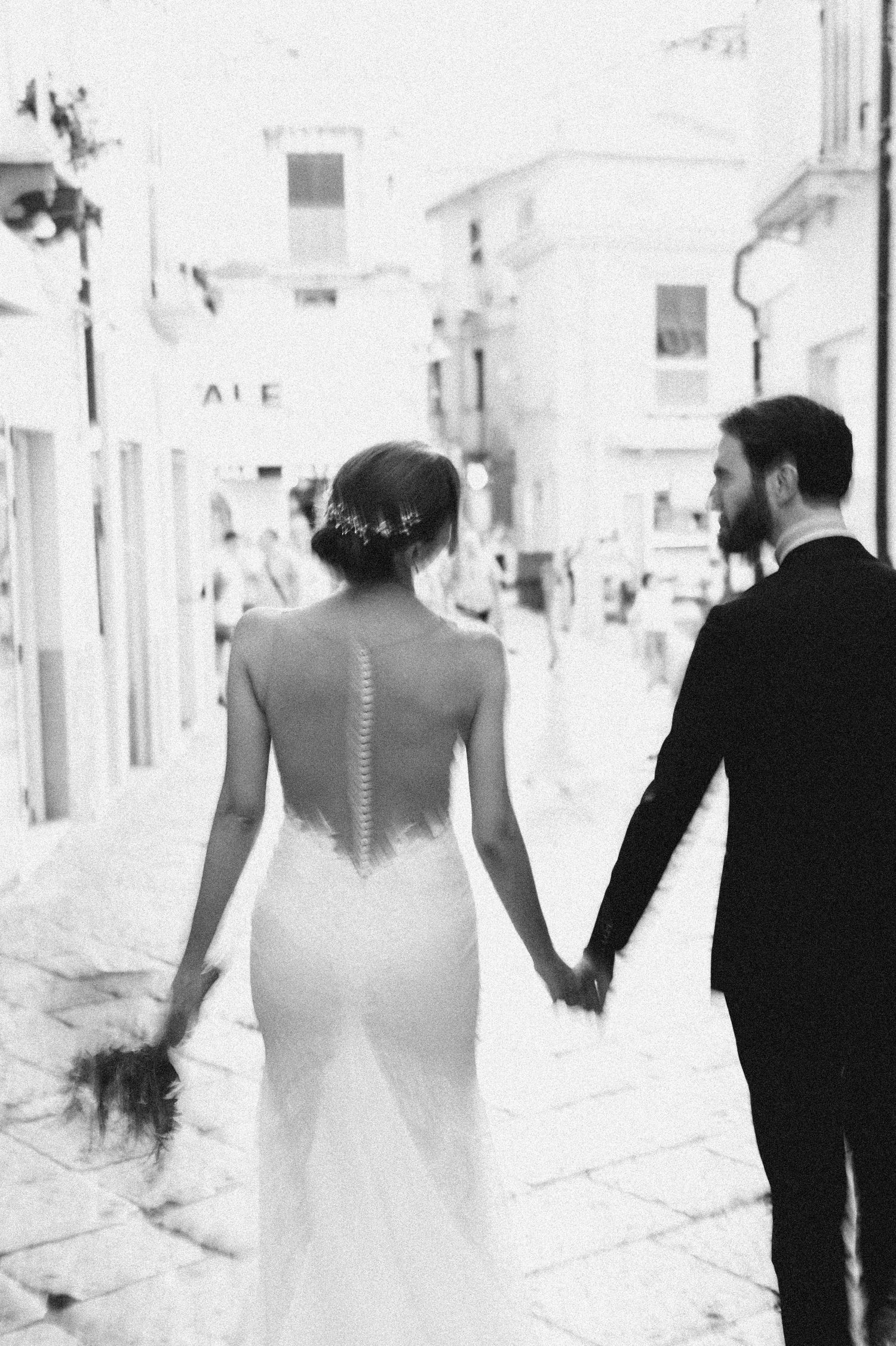 Black and white photograph of the newlyweds walking through Tropea
