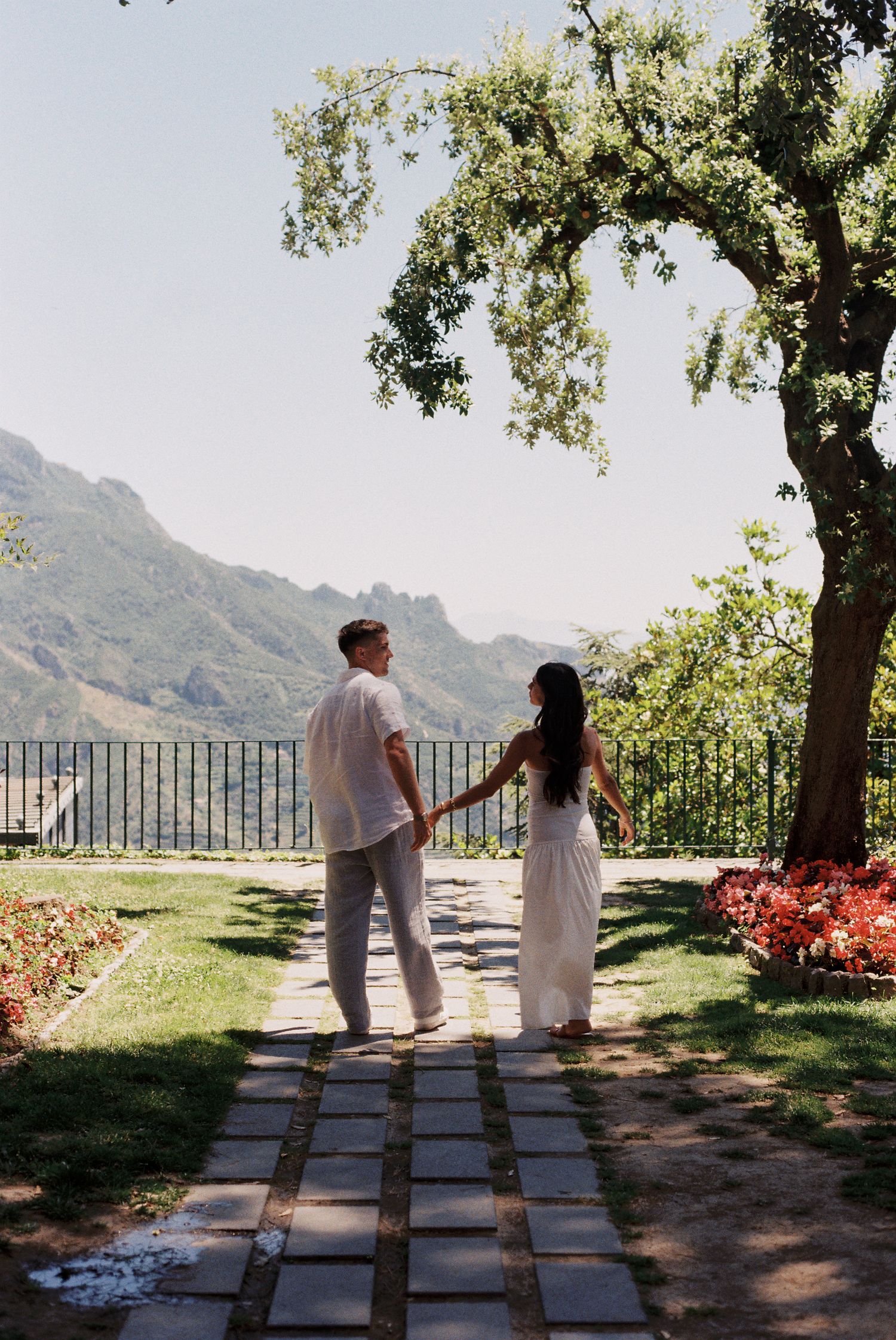 Couple walking hand in hand through a garden in Ravello