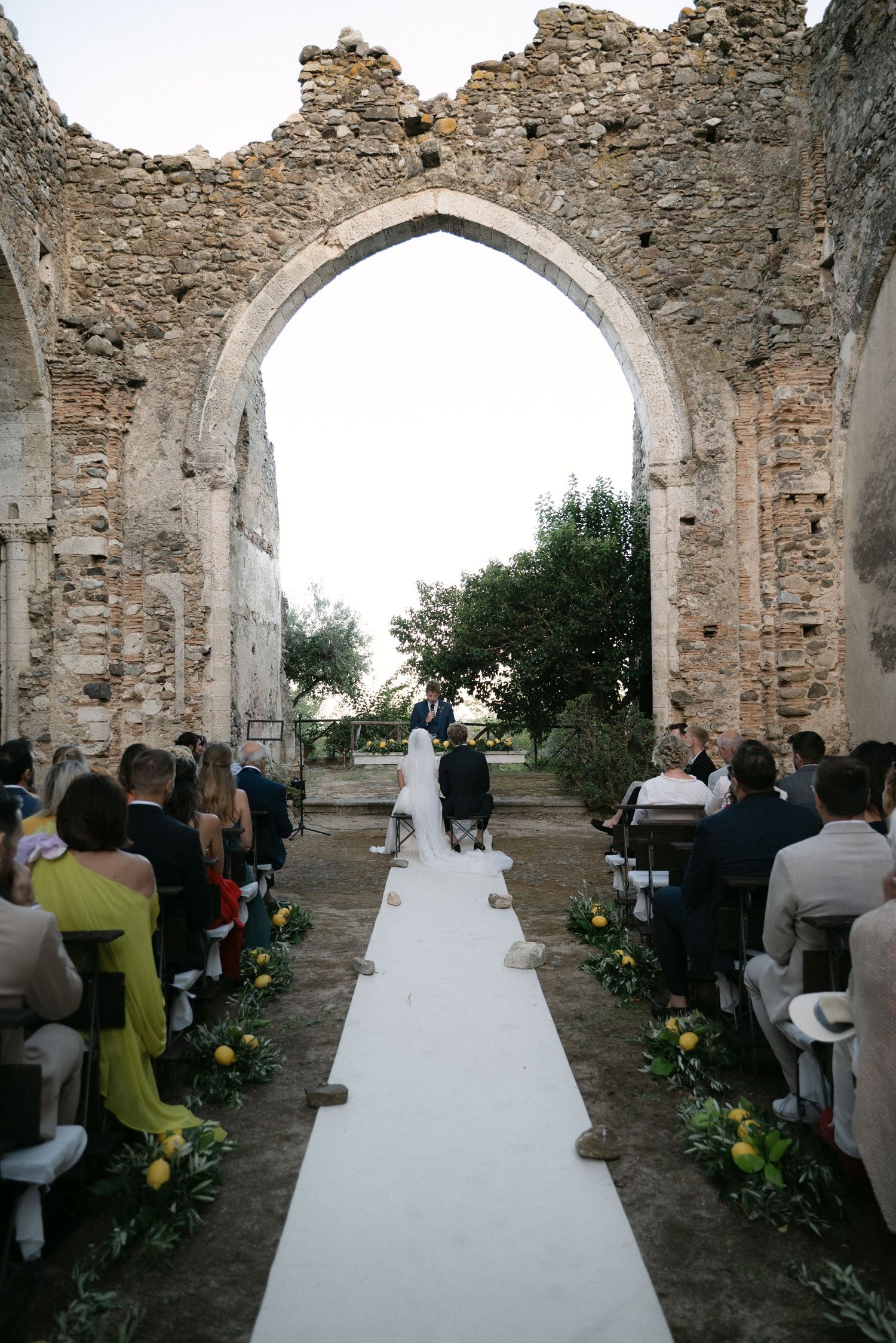 Wedding ceremony seen through the historic stone arches of Borgo del Convento